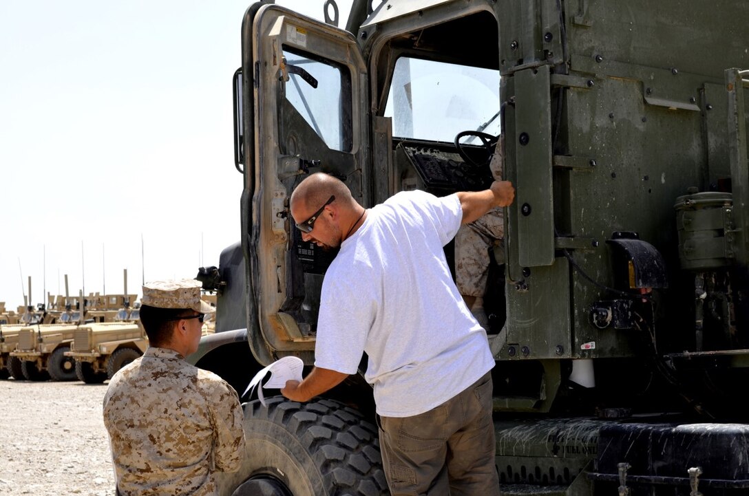 Courtesy photo - A Marine and contractor with Logistics Command Forward receive a tactical vehicle during their deployment to Camp Leatherneck, Helmand province, Afghanistan. LOGCOM Forward was responsible for redeploying tactical vehicles and gear to Marine Corps Logistics Base Albany, Ga., for reset and reconstitution as deployed units begin to redeploy home, prior to their flag-folding ceremony, June 1, 2014.