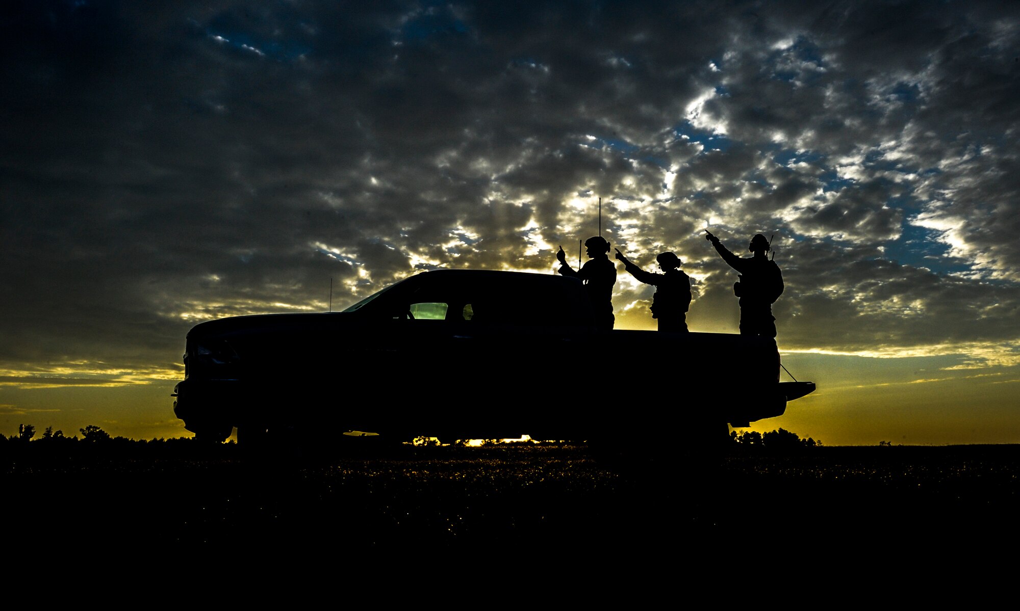 U.S. Air Force Combat Controllers point to an incoming aircraft while standing on the back of a truck during Emerald Warrior 2014 at at Stennis International Airport, MS, May 2, 2014. Emerald Warrior is an annual, joint exercise to train special operations, conventional and partner nation forces in combat scenarios designed to hone special operations air and ground combat skills, and is the Department of Defense's only irregular warfare exercise. (U.S. Air Force photo by Senior Airman Colville McFee / Released)