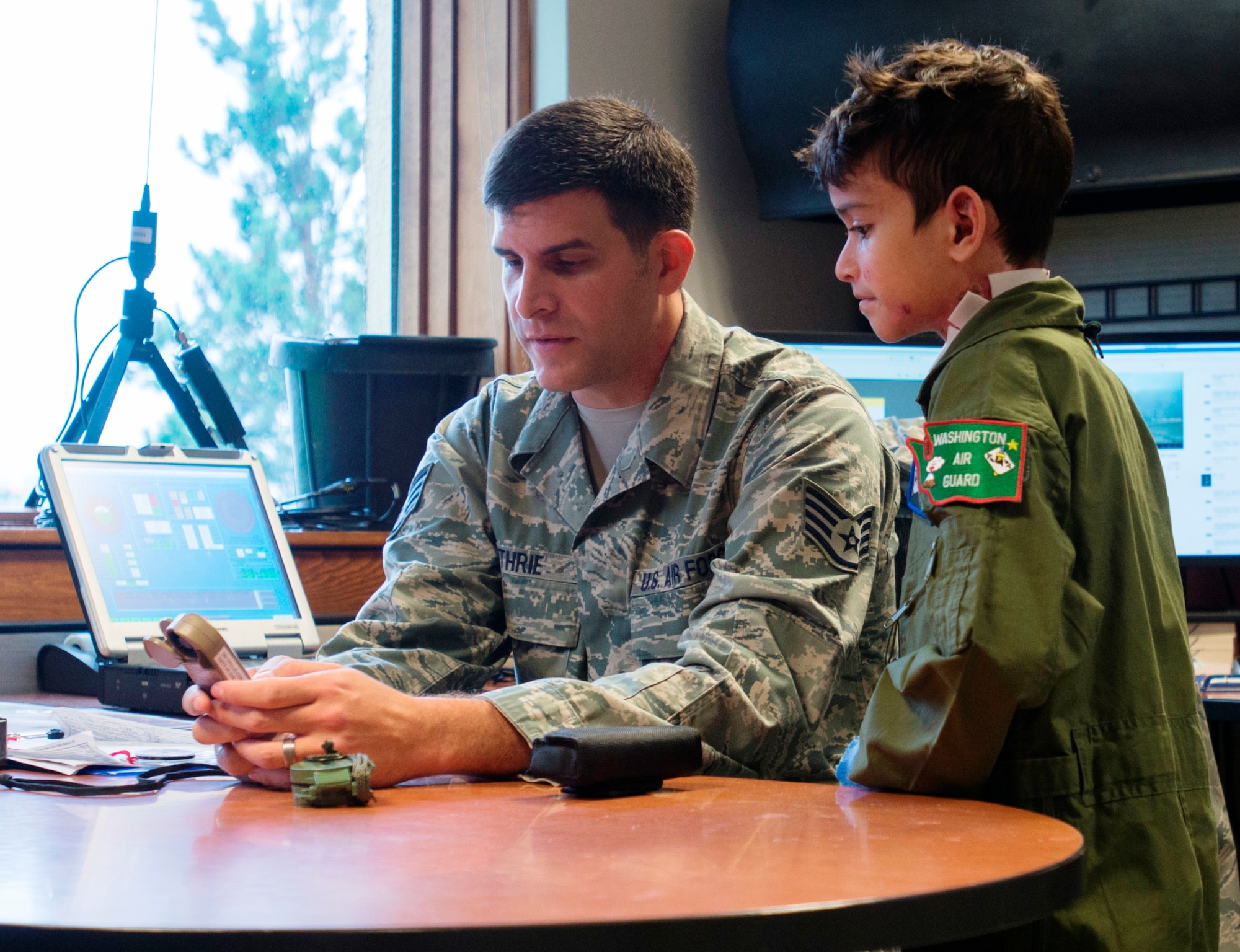 Staff Sgt. William Guthrie shows Sam Diaz the functions of a handheld weather meter during pilot for a day at Fairchild Air Force Base, Washington, June 18, 2014. Sam was participating in the 141st Air Refueling Wing program which allows children going through challenging times to become an honorary wing pilot. (U.S. Air Force photo by Tech. Sgt. Michael Brown/Released)