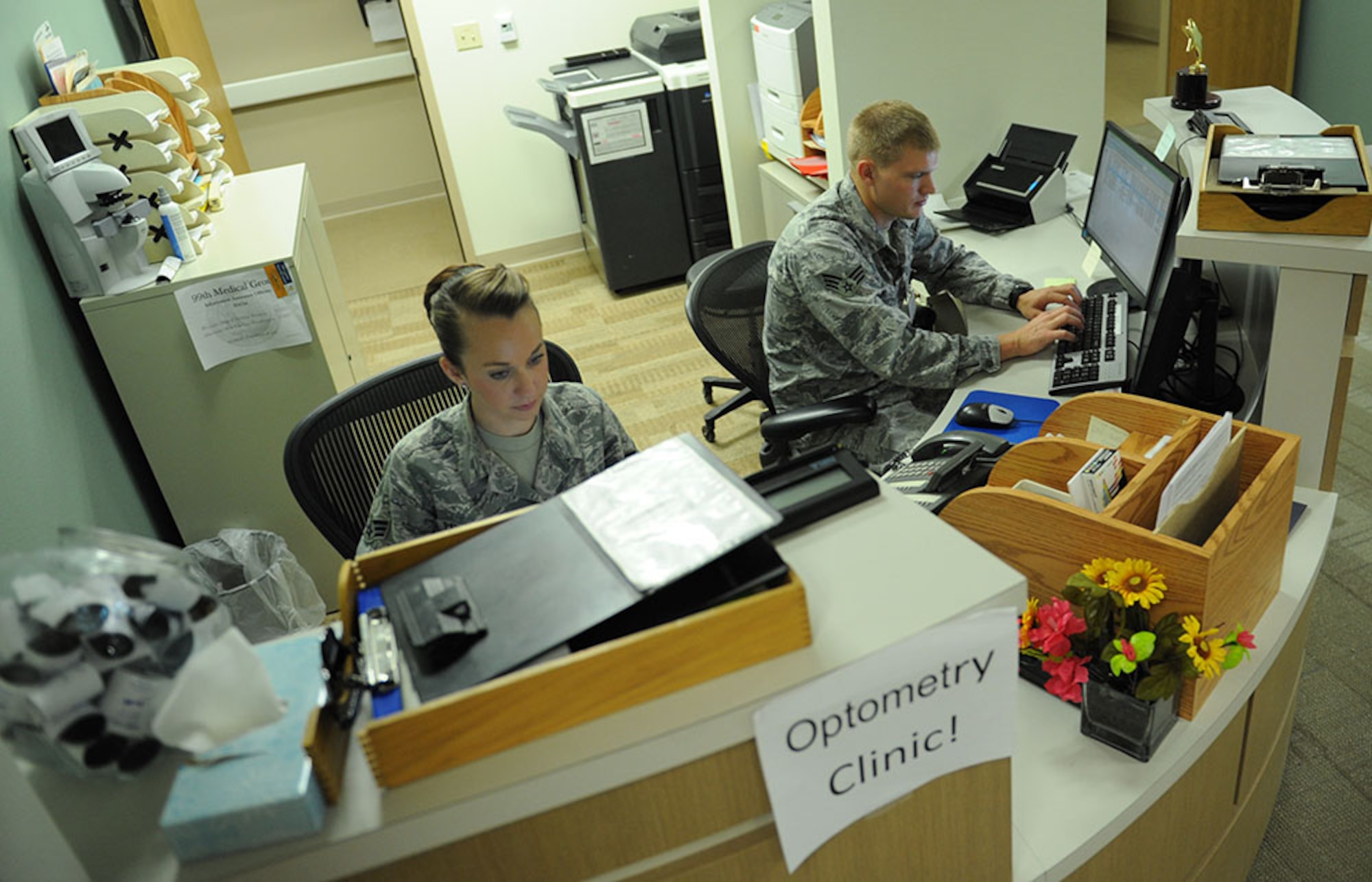 (Left) Senior Airman Nichelle Patterson, 99th Aerospace Medicine optometry technician, and Senior Airman Cody Egdorf, 99th AMDS optometry technician, check in patients on June 24, 2014, at Nellis Air Force Base, Nev. The 99th AMDS optometry clinic moved to building 340 June 12, 2014 to be closer to other 99th AMDS flights and to be more convenient for customers. (U.S. Air Force photo by Airman First Class Rachel Loftis)