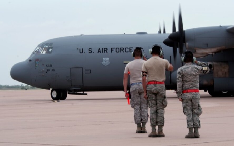 U. S. Air Force Airmen from the 317th Aircraft Maintenance Squadron salute a C-130J Super Hercules as it taxis towards the runway June 21, 2014, at Dyess Air Force Base, Texas. Aircrews at Dyess launched 21 C-130s from multiple units to fly in a large formation. (U.S. Air Force photo by Senior Airman Peter Thompson/Released)