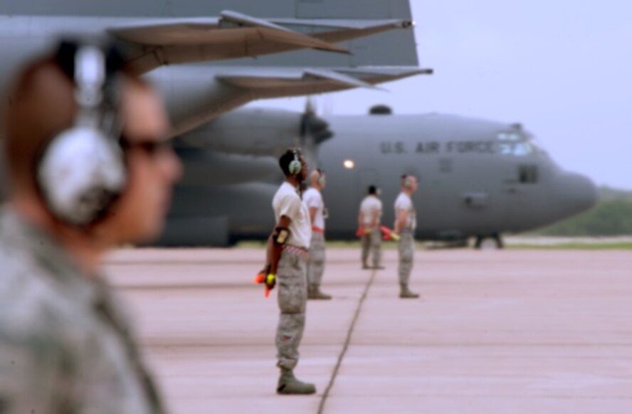 U.S. Air Force Airmen from the 317th Aircraft Maintenance Squadron prepare to marshal their aircraft June 21, 2014, at Dyess Air Force Base, Texas. Twelve C-130Js from the 317th Airlift Group joined more than 50 other aircraft across 14 other wings  and seven major commands  to take part in the largest Joint Forcible Entry Exercise led by the United States Air Force. (U.S. Air Force photo by Senior Airman Peter Thompson/Released)