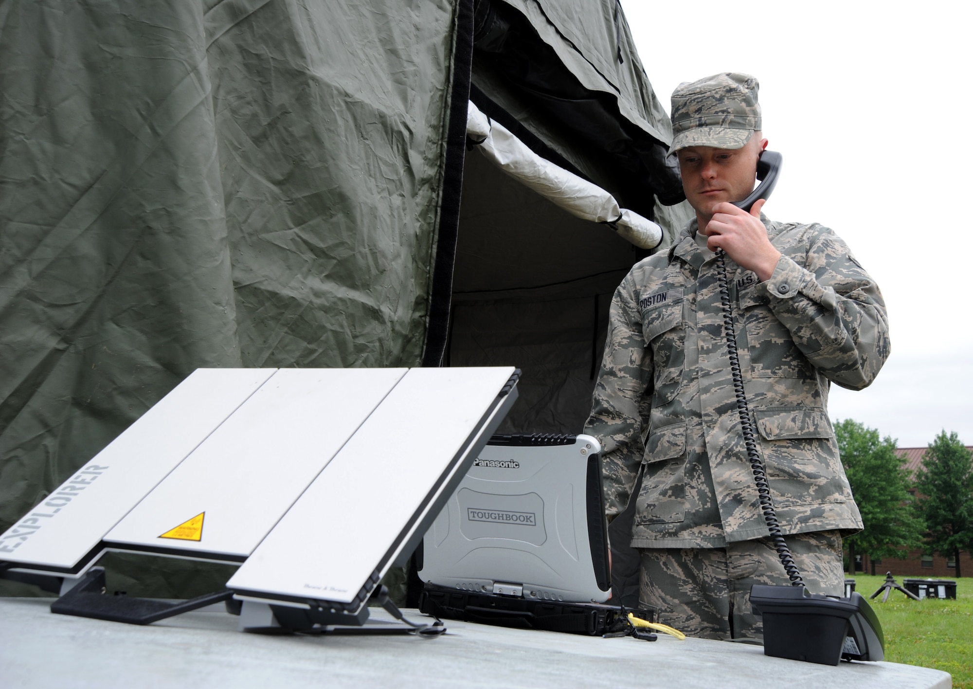 Senior Airman Christopher Poston, 239th Combat Communications Squadron radio frequency transmissions journeyman, uses a satellite telephone during a simulated deployment to Whiteman Air Force Base, Mo., June 11, 2014. The 239th CCS was here to provide the 131st Bomb Wing and 509th Bomb Wing with full communications capabilities. (U.S. Air Force photo by Senior Airman Bryan Crane/released)