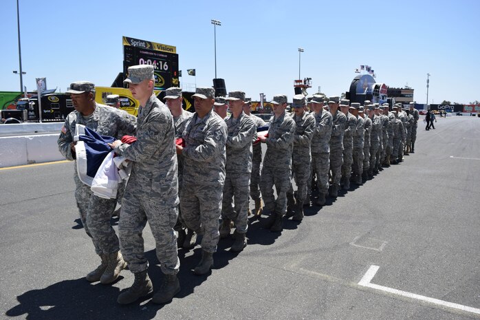 Airmen from Beale Air Force Base and Army soldiers walk a large American flag off the racetrack at Sonoma Raceway, Sonoma, Calif., June 22, 2014. The volunteers unfurled a large flag during pre-race ceremonies at the NASCAR race. (U.S. Air Force photo by Capt. Brian Wagner/Released)