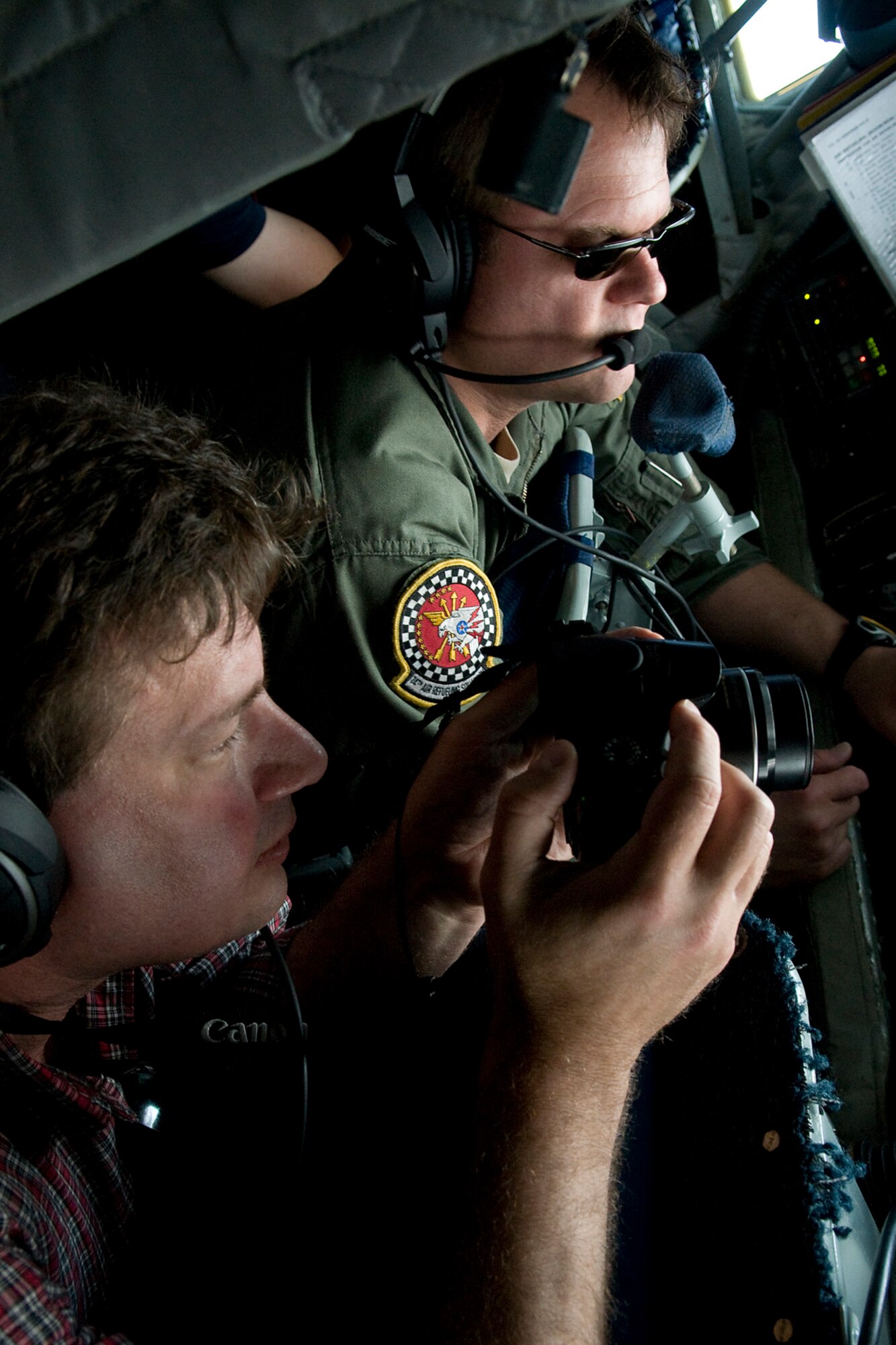 Joe Cogliano, a senior reporter from the Dayton Business Journal, snaps pictures of Master Sgt. Christopher Nack, 74th Air Refueling Squadron boom operator, performing  inflight refueling operations onboard a 434th Air Refueling Wing KC-135R Stratotanker aircraft during a training mission and media flight over Kentucky June 18, 2014. The main mission of the KC-135 is to provide inflight refueling to long-range bomber, fighter and cargo aircraft. (U.S. Air Force photo/Senior Airman Jami K. Lancette)