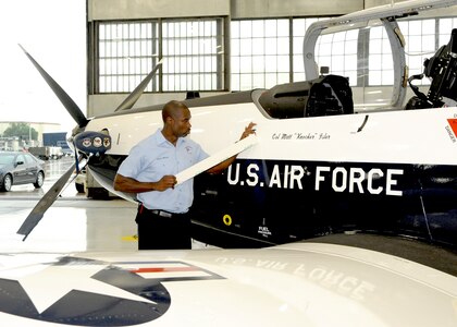 Louis Marcy from the 12th Flying Training Wing Maintenance Directorate, unveils Col. Matthew Isler’s name on the side of a T-6A Texan II June 25, 2014, during the 12th FTW change of command ceremony at Joint Base San Antonio-Randolph, Texas. (U.S. Air Force photo/Melissa Peterson)