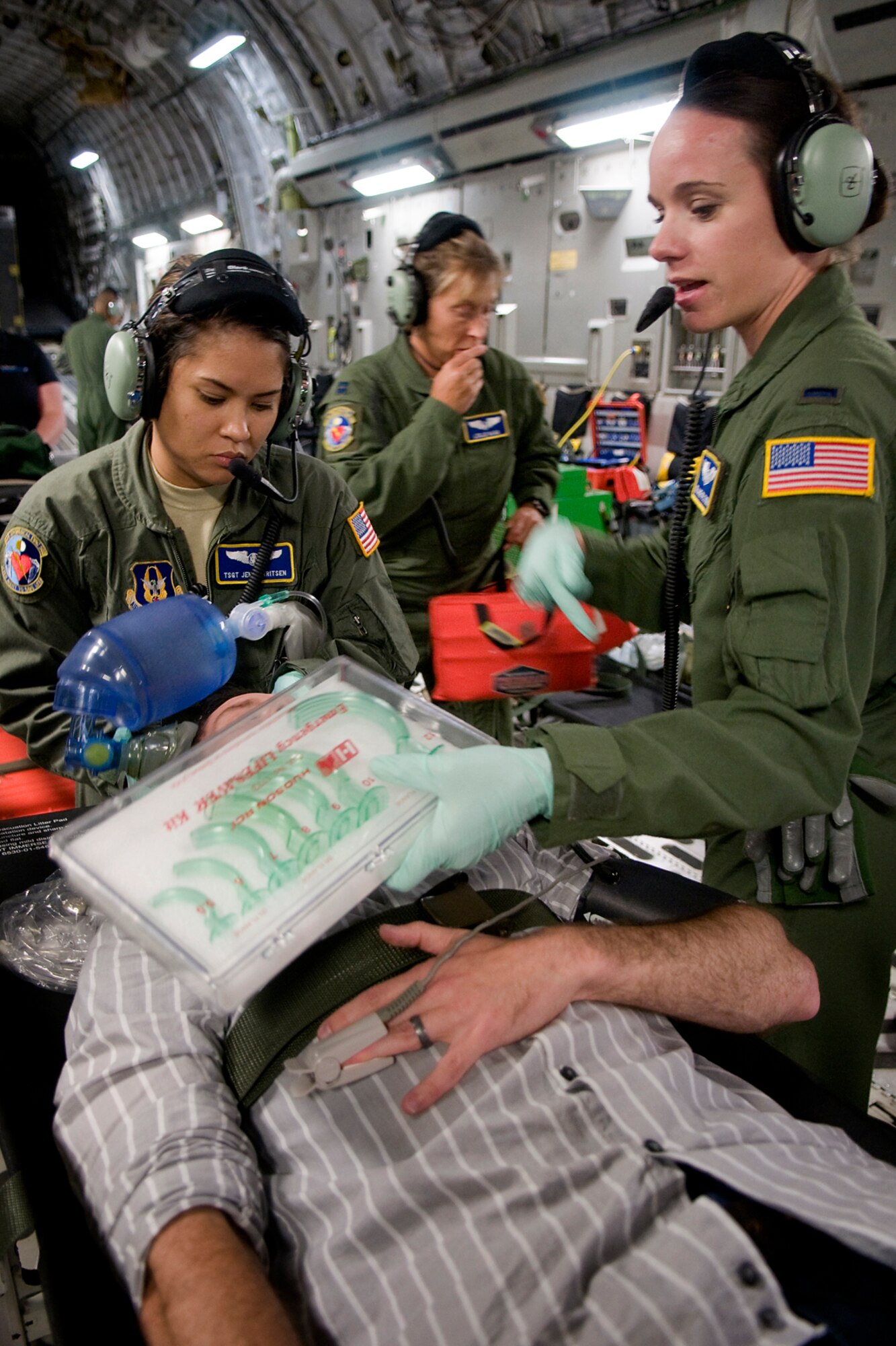 Tech. Sgt. Jennifer Gerritsen, 445th Aeromedical Evacuation Squadron aeromedical evacuation technician, left, and 1st Lt. Melanie Feltner, 445th AES flight nurse, train on treating Rocky Walls, with 12 Stars Media, who served as a patient with a simulated collapsed lung during a training flight over Kentucky Aug. 18, 2014. Walls and media representatives from both Indiana and Ohio got a chance to fly with the 434th Air Refueling Wing from Grissom Air Reserve Base, Ind., and the 445th Airlift Wing from Wright-Patterson Air Force Base, Ohio. (U.S. Air Force photo/Tech. Sgt. Mark R. W. Orders-Woempner)