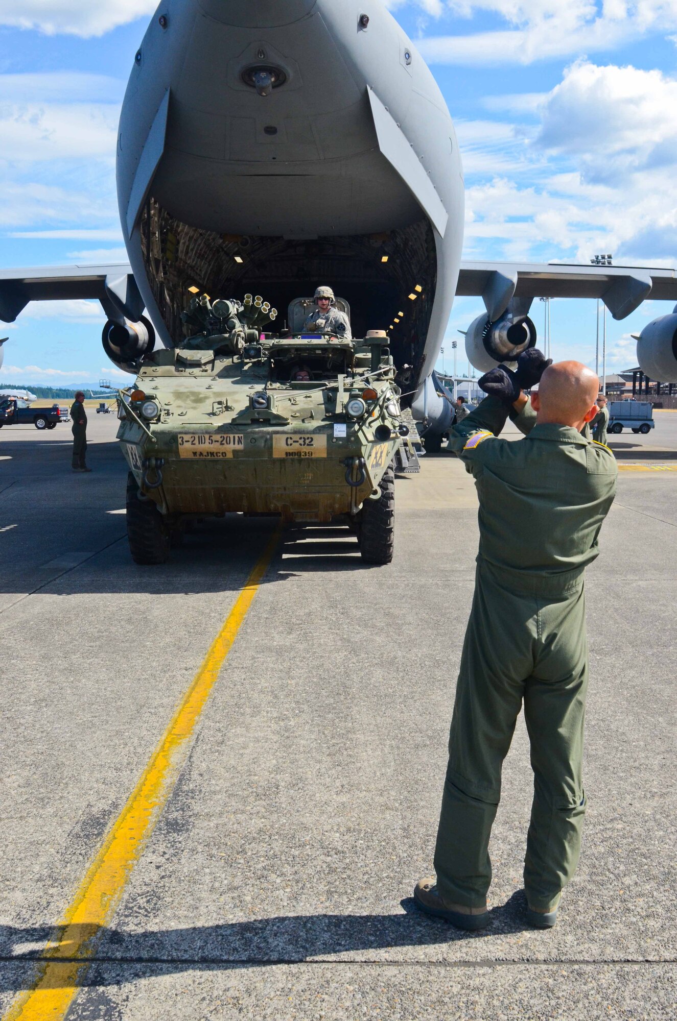 U.S. Air Force Airman 1st Class Ker Vang, 10th Airlift Squadron loadmaster, ground guides a Stryker combat vehicles off a C-17 Globemaster III during a training exercise June 19, 2014, at Joint Base Lewis-McChord, Wash. The exercise allowed Soldiers and Airmen to work together and practice loading and unloading Strykers. (U.S. Army photo/Staff Sgt. Justin Naylor)