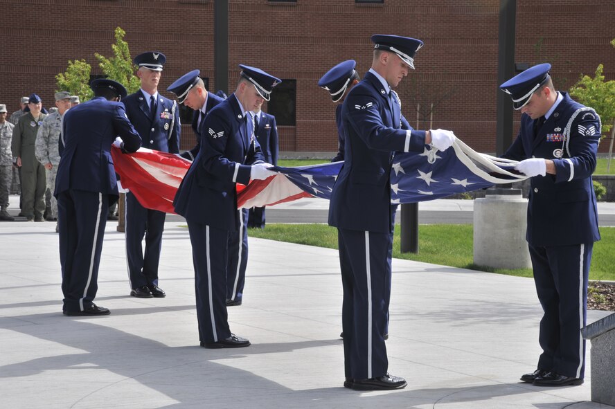 Team Fairchild Honor Guard members fold the flag during a retreat ceremony held at Fairchild Air Force Base, Wash., June 24, 2014. During the retreat, a ceremonial bell was rang for each of the four Airmen that lost their lives in the B-52 Stratofortress crash in 1994. This date represented the 20th anniversary of the fatal crash. (U.S. Air Force photo by Senior Airman Mary O'Dell/Released)