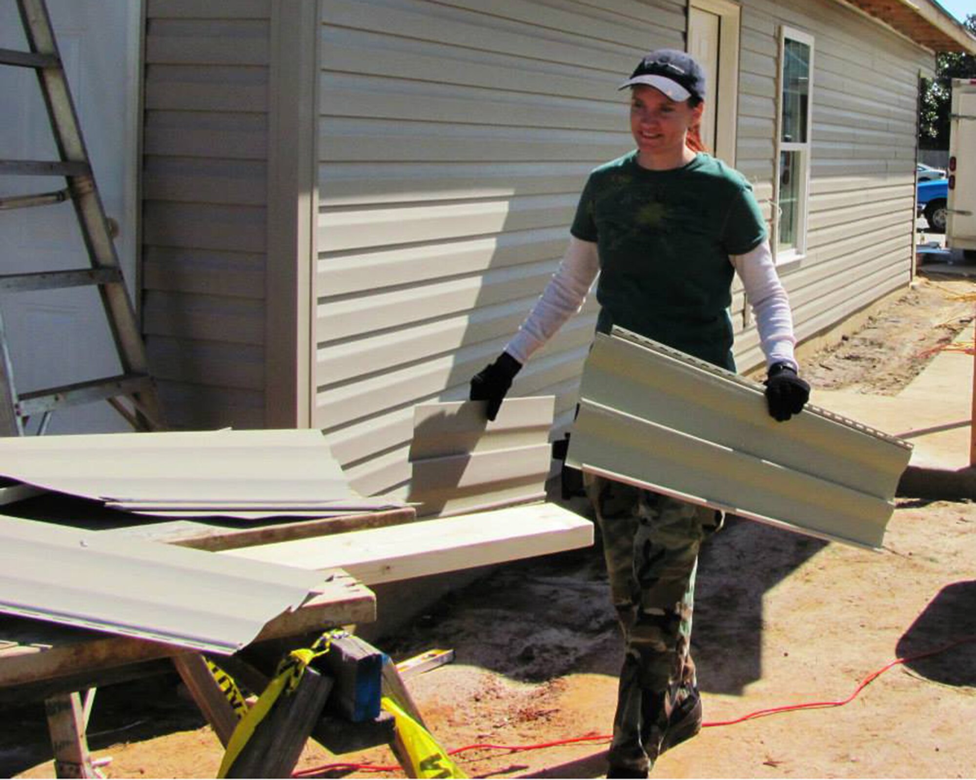 With a new Habitat for Humanity home insulated, Staff Sgt. Melissa Erwin, Air Force Reserve Command vulnerability management technician, helps install siding in November 2013.  (Courtesy photo)