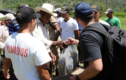 A man from the village of Proterillos receives a bag of food from a Joint Task Force-Bravo member.  Nearly 130 members of Joint Task Force-Bravo, with the support of Joint Task Force-Bravo’s Joint Security Forces, completed a volunteer five mile round trip hike to deliver more than 4,000 pounds of food, supplies and clothing to families in need in the mountain village of Proterillos outside La Paz, Honduras, June 21, 2014.  The effort was part of the 55th Joint Task Force-Bravo Chapel Hike, a venerable tradition during which the servicemembers donate money to purchase food and supplies and then carry them on a hike through the mountains to deliver to local, underserviced communities.  (Photo by U. S. Air National Guard Capt. Steven Stubbs)