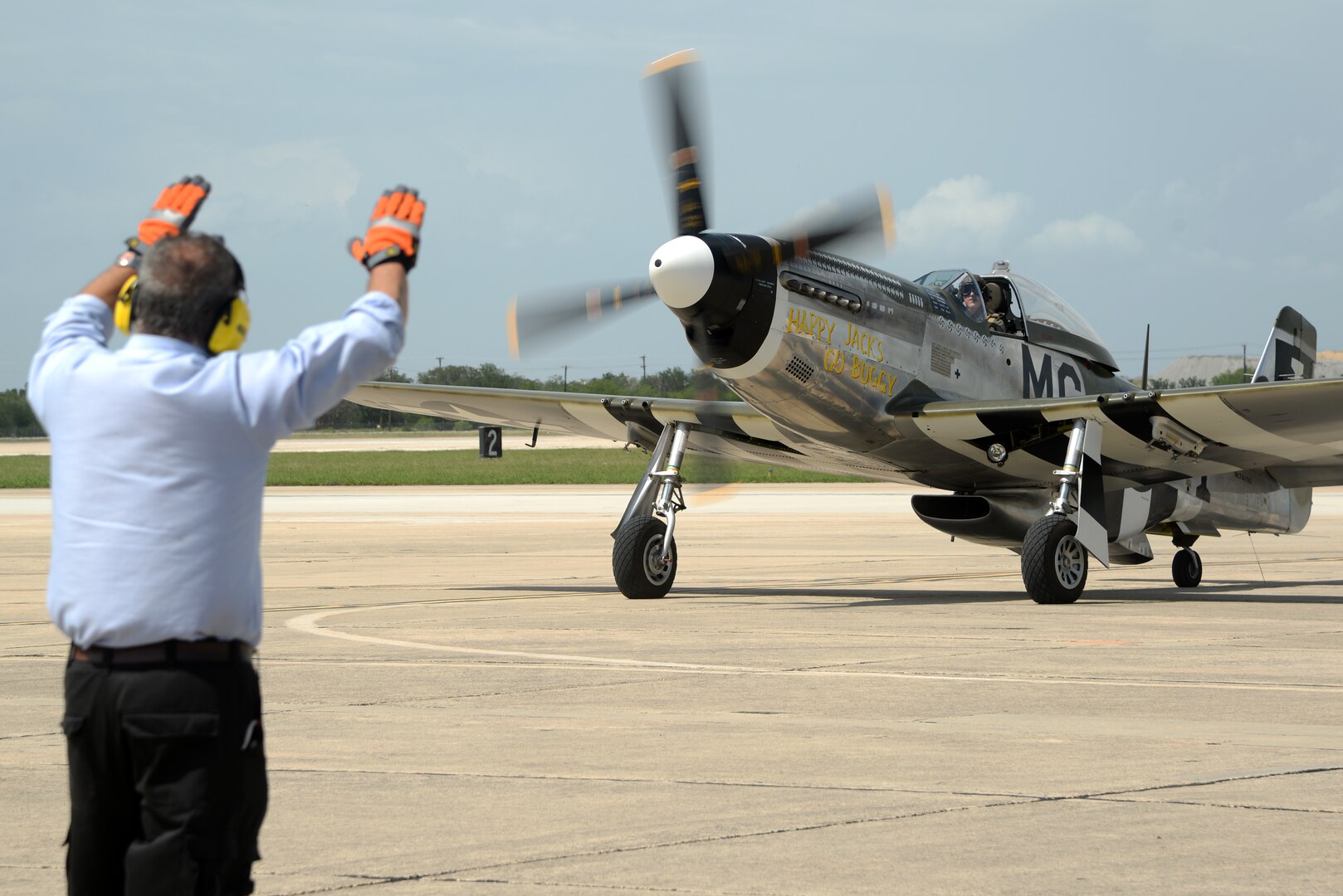 Peter Crevisto, Transient Alert program manager, directs a fully restored P-51 Mustang piloted and owned by Bruce Winter, a former F/A-18 Hornet pilot in the U.S. Navy, to its final parking spot June 20 at Joint Base San Antonio-Randolph. Thirteen ace pilots visited Joint Base San Antonio-Randolph June 20. The American Fighter Aces Association was founded in 1960 to recognize the 1,450 combat pilots who received the special distinction of becoming an ace by destroying five or more hostile aircraft in air-to-air combat. (U.S. Air Force photo by Johnny Saldivar)