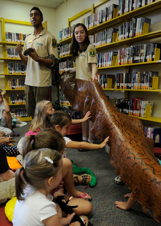 Devin Mock educates Joint Base Andrews families on reptiles while Kyra Harvey unrolls a snake skin at the library on Joint Base Andrews, Md., June 24, 2014. Harvey and Mock are naturalists with Cosca Regional Park’s Clearwater Nature Center who brought a variety of reptiles to interact with. (U.S. Air Force photo/Senior Airman Nesha Humes)