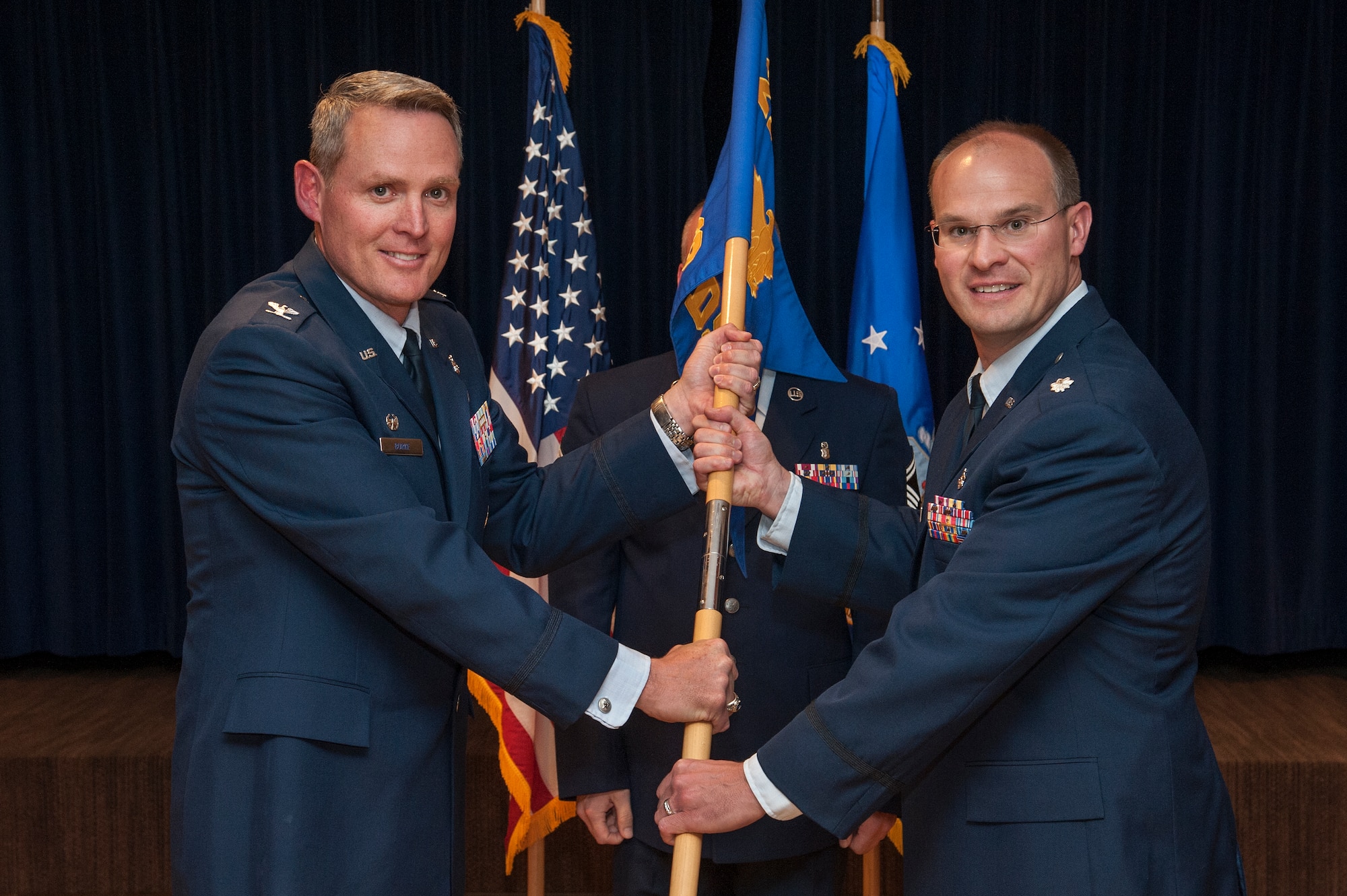 PETERSON AIR FORCE BASE, Colorado – Col. Michael Burke (left), 21st Medical Group commander, passes the 21st Medical Support Squadron flag to Lt. Col. Mark Reynolds during the 21st MDSS change of command ceremony June 20 at The Club. Reynolds replaces outgoing commander Lt. Col. Barbara Hoeben. The 21st MDSS consists of seven flights which manage medical group facilities, logistics, financial and manpower programs, information systems, managed care, ancillary services and readiness, and provides health services for more than 171,000 eligible beneficiaries. (U.S. Air Force photo/Craig Denton)