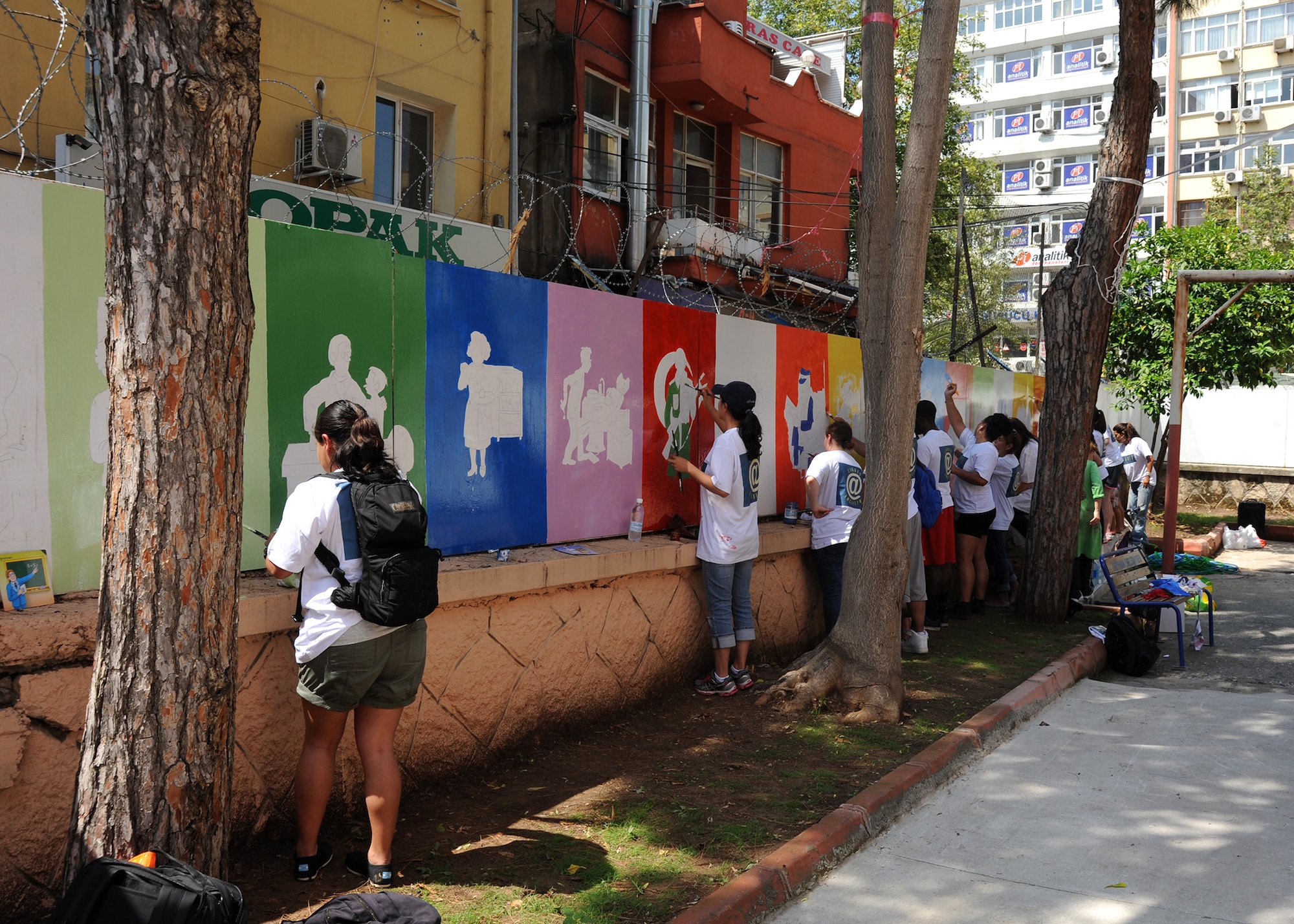 Volunteers paint murals along courtyard walls at the Kazim Karabekir School for Autism, June 9, 2014, Adana, Turkey. The volunteers are part of a group called organization Love Impact Give Help Teach Serve, or LIGHTS which is located at Incirlik Air Base, Turkey.  The group of 15 volunteers in the local community by helping special needs schools with art projects around Adana. (U.S. Air Force photo by Staff Sgt. Veronica Pierce/Released)