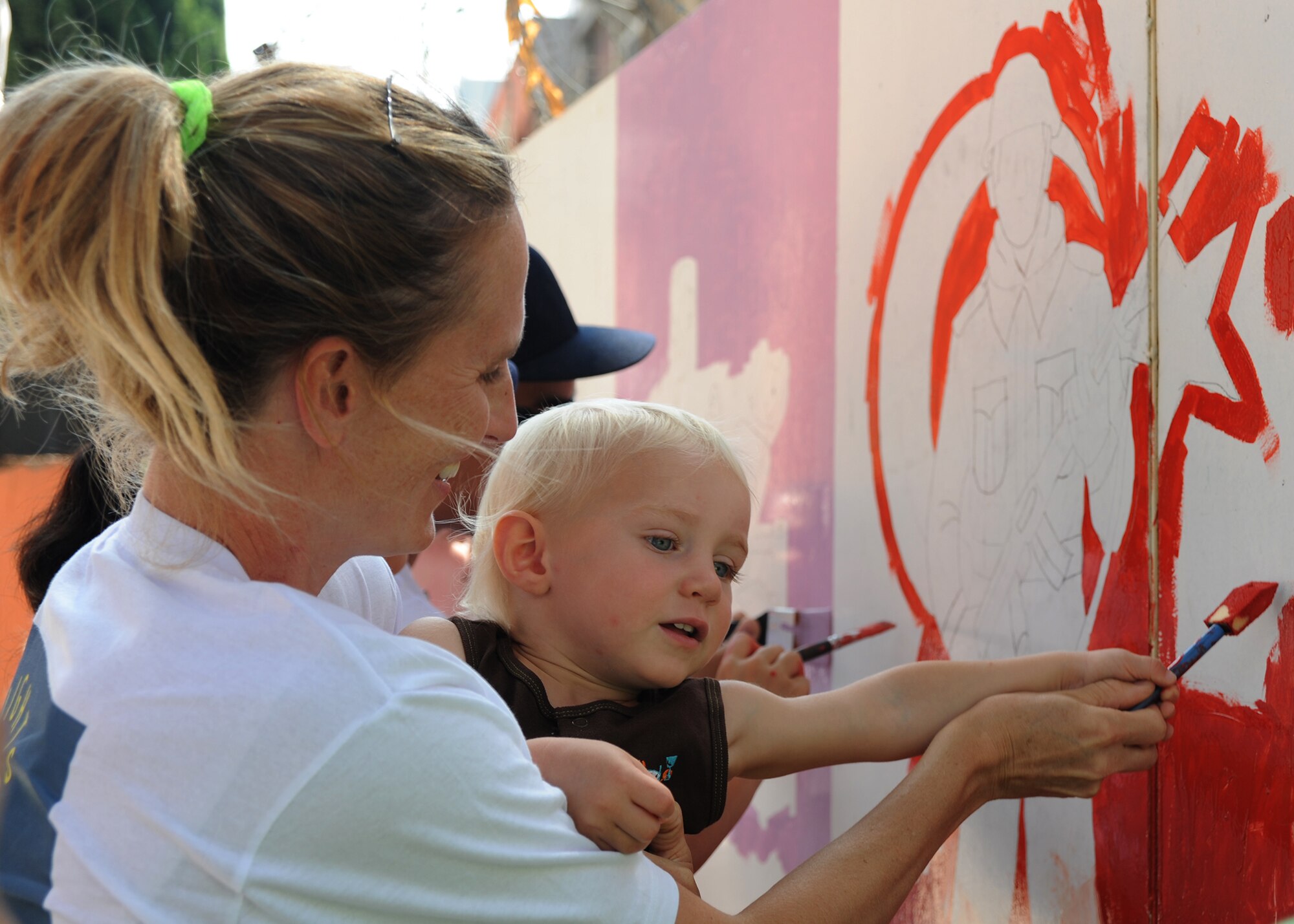 Linne Gherdovich and son Hudson, paint a mural of a Turkish soldier at the Kazim Karabekir School for Autism, June 9, 2014, Adana, Turkey. Gherdovich is a coordinator with the organization Love Impact Give Help Teach Serve, or LIGHTS located at Incirlik Air Base, Turkey. The group of active duty members, civilians and dependents of all ages focuses on helping the community with simple art projects at special needs schools around Adana. (U.S. Air Force photo by Staff Sgt. Veronica Pierce/Released)