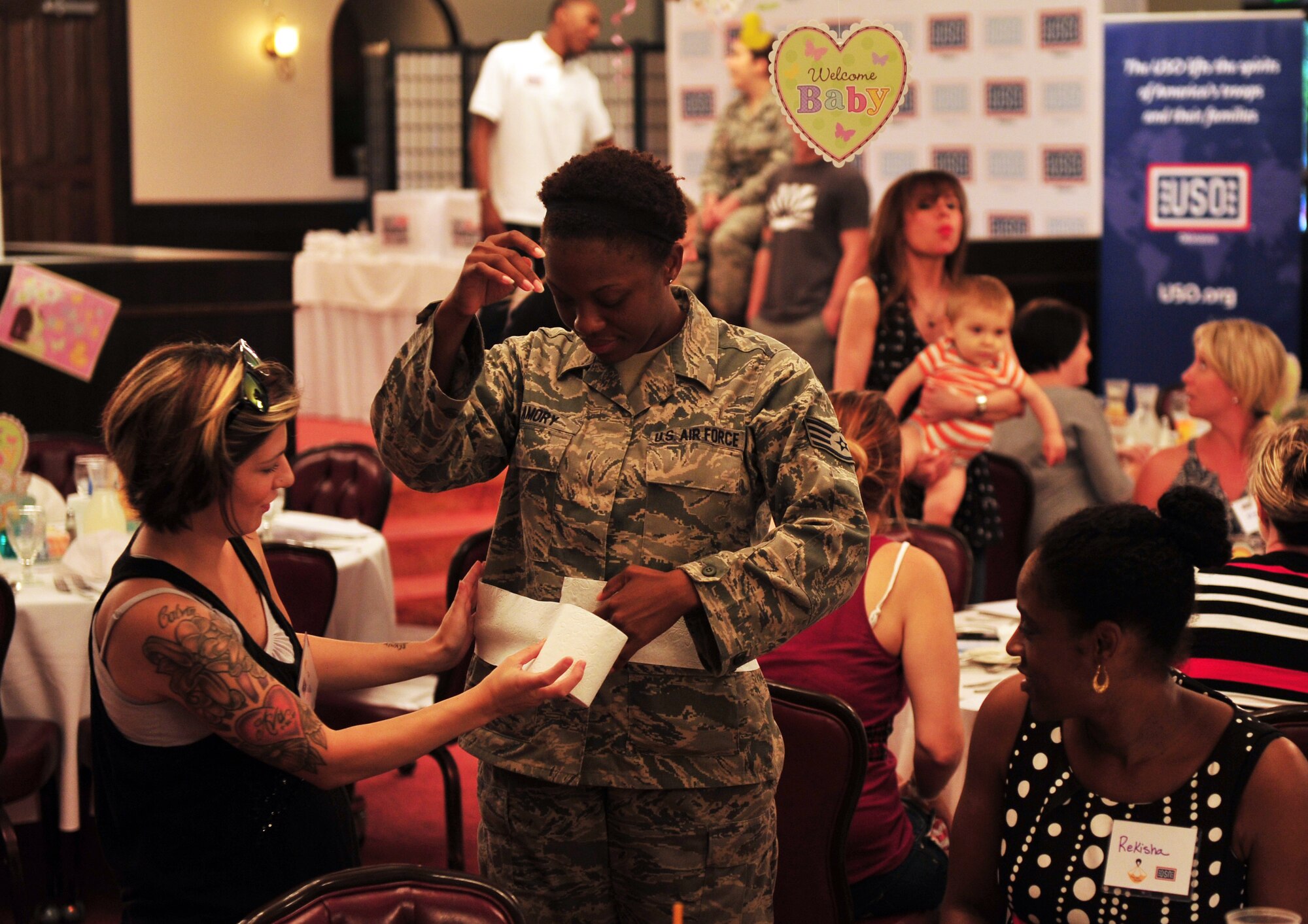 Expectant mothers guess each other's waist measurements with toilet paper during a baby shower, Kadena Air Base, Japan, June 18, 2014. Through the Special Delivery program, the USO, best-selling author Heidi Murkoff and her What to Expect Foundation teamed up to give these special moments back to military moms as a thank you for their service and sacrifice. (U.S. Air Force photo by Staff Sgt. Rachelle Coleman)