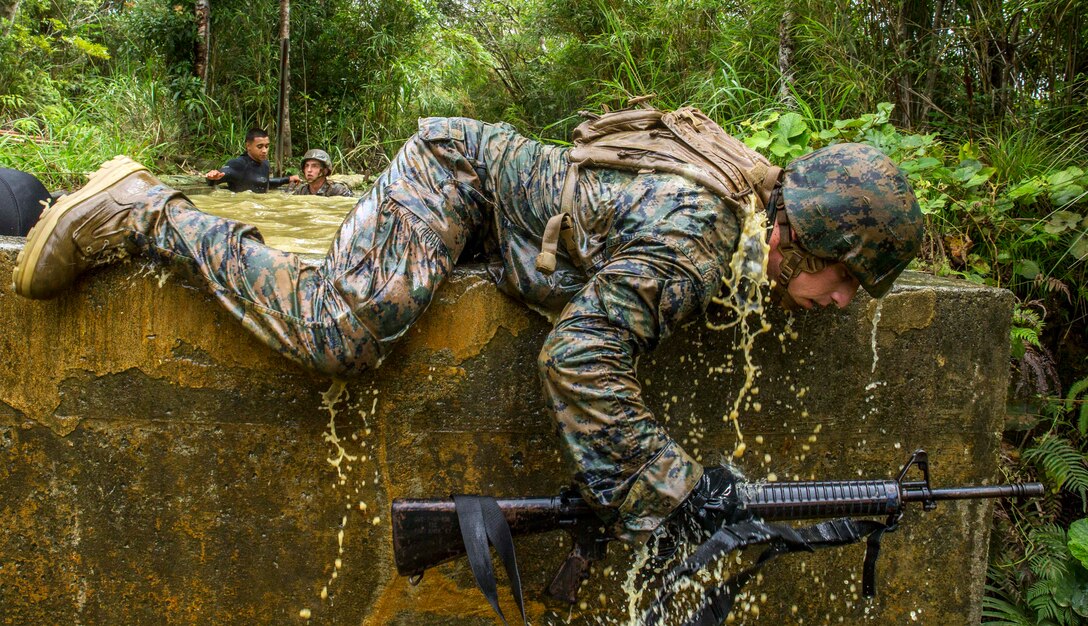 U.S. Marine Corps Cpl. Kevin E. Kusler crawls over a stone wall during the endurance course at the Jungle Warfare Training Center on Camp Gonsalves on Okinawa, Japan, June 20, 2014.  During the course, Marines and sailors navigated harsh jungle environment and man-made obstacles in the heat and humidity of the island. 