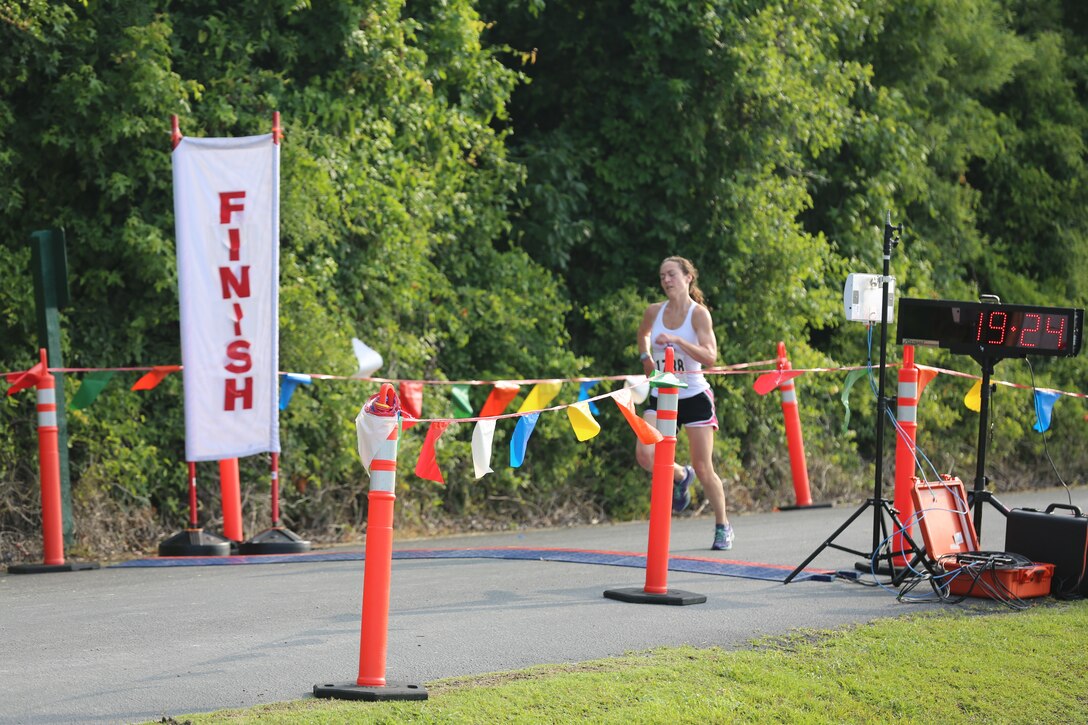 Katherine Price runs across the finish line after completing the Coastal Women’s Shelter 5k run June 21 at Creekside Park in James City, N.C. Price was the first women to cross the finish line as she assisted the CWS raise awareness of domestic violence. The CWS provides domestic abuse victims with resources designed to strengthen them mentally and physically as they seek new relationships and better old ones. 