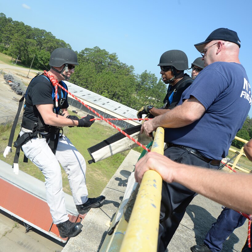 Officer Bruce Owens, a member of the Special Reaction Team, Marine Corps Police Department (left) begins his rappel, June 6, under the watchful eye of team members and Marine Corps Logistics Base Albany Fire Department personnel.