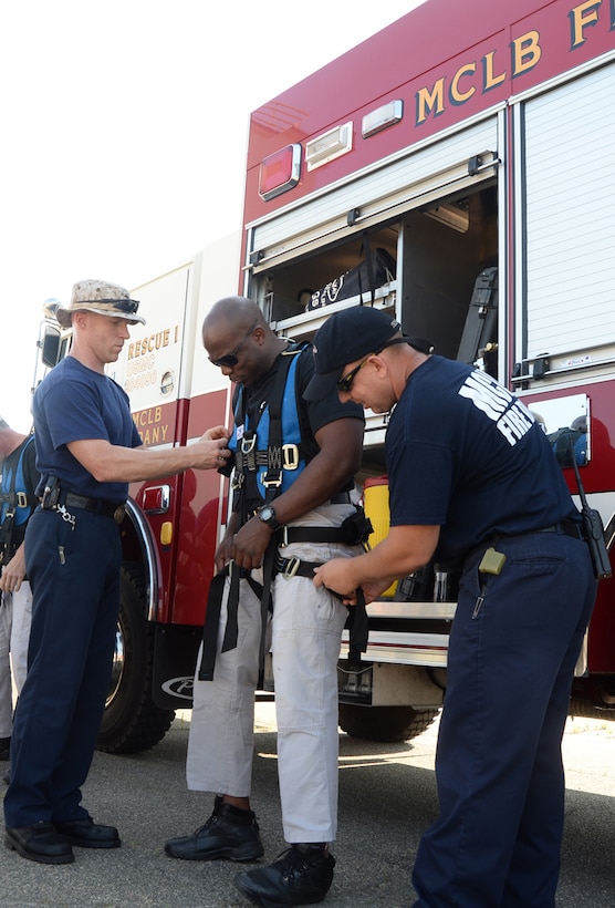 Cpl. Rhamaro Murphy, a member of the Special Reaction Team, Marine Corps Police Department, (center) receives assistance from Marine Corps Logistics Base Albany Fire Department personnel while putting on gear in preparation to rappel from a tower on base, June 6.