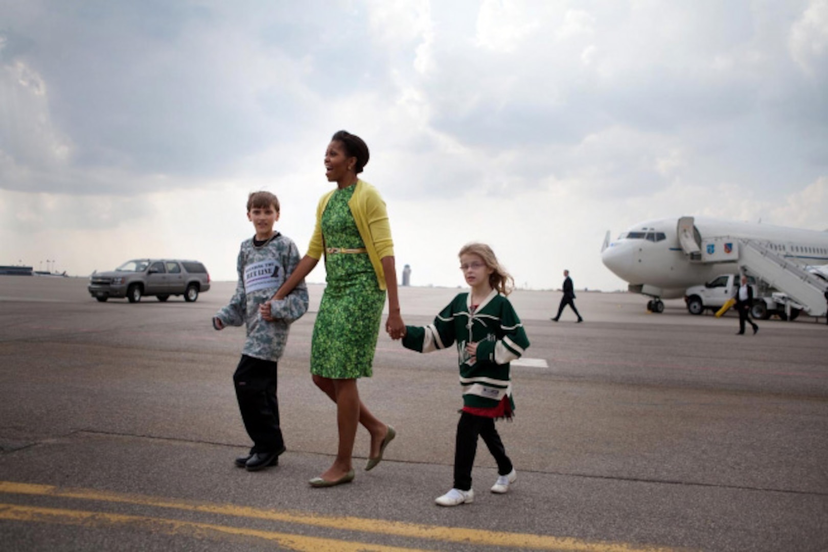 First Lady Michelle Obama walks across the tarmac with Megan Soukup, 9, and Joseph Hudella, 10, participants in the Defending the Blue Line program, as she prepares to greet military families at Minneapolis-St. Paul International Airport in Minneapolis, Minn., March 16, 2012. The First Lady traveled to Minnesota to meet with National Guard families and local community leaders dedicated to supporting military families.