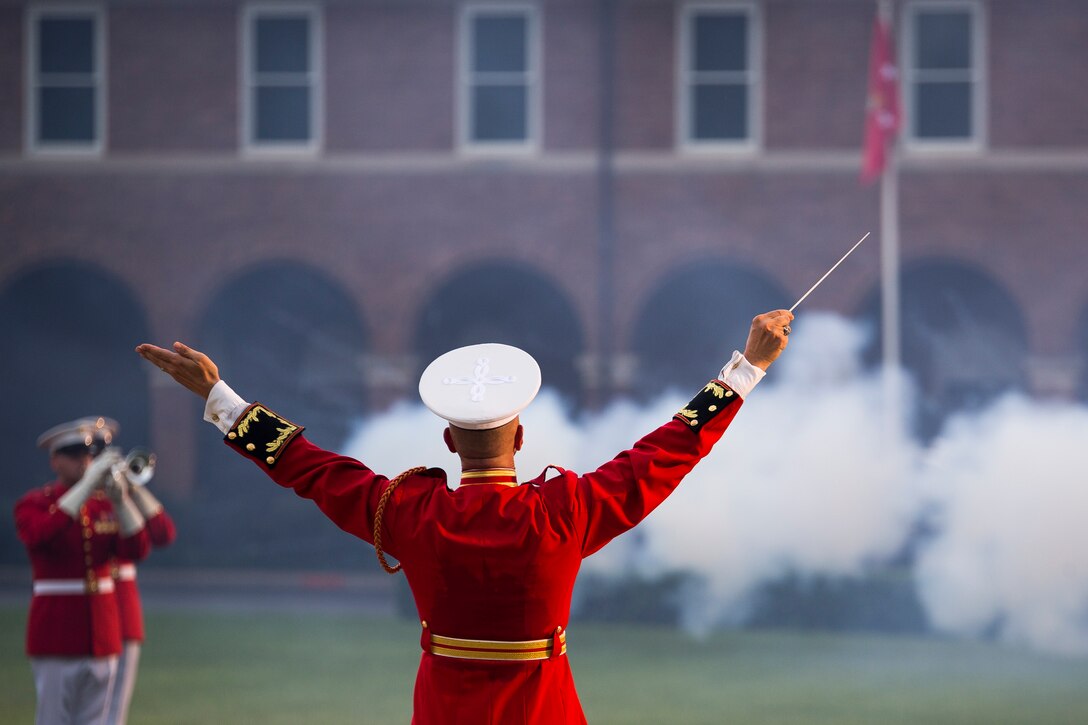 Maj. Brian Dix, U.S. Marine Drum & Bugle Corps commanding officer, performs as the Body Bearers fire the ceremonial cannons during a concert at Marine Barracks Washington, D.C., June 25, 2014. The concert was to honor the 80th anniversary of the Drum & Bugle Corps. (Official Marine Corps photo by Cpl. Dan Hosack/Released)