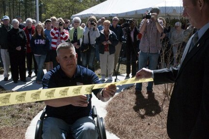 Army Staff Sgt. Scott Millican, who was severely injured in Afghanistan in 2010, cuts the ceremonial ribbon and receives the keys to his new specially adapted home during a ceremony in Statesboro, Ga., March 10, 2012. A crowd of Soldiers and well wishers, including guest speaker Rep. John Barrow of Georgia, celebrated as Millican unlocked his new home. Homes for Our Troops, which fabricated the home, provide specially adapted homes to severely injured veterans at no cost to the veteran.