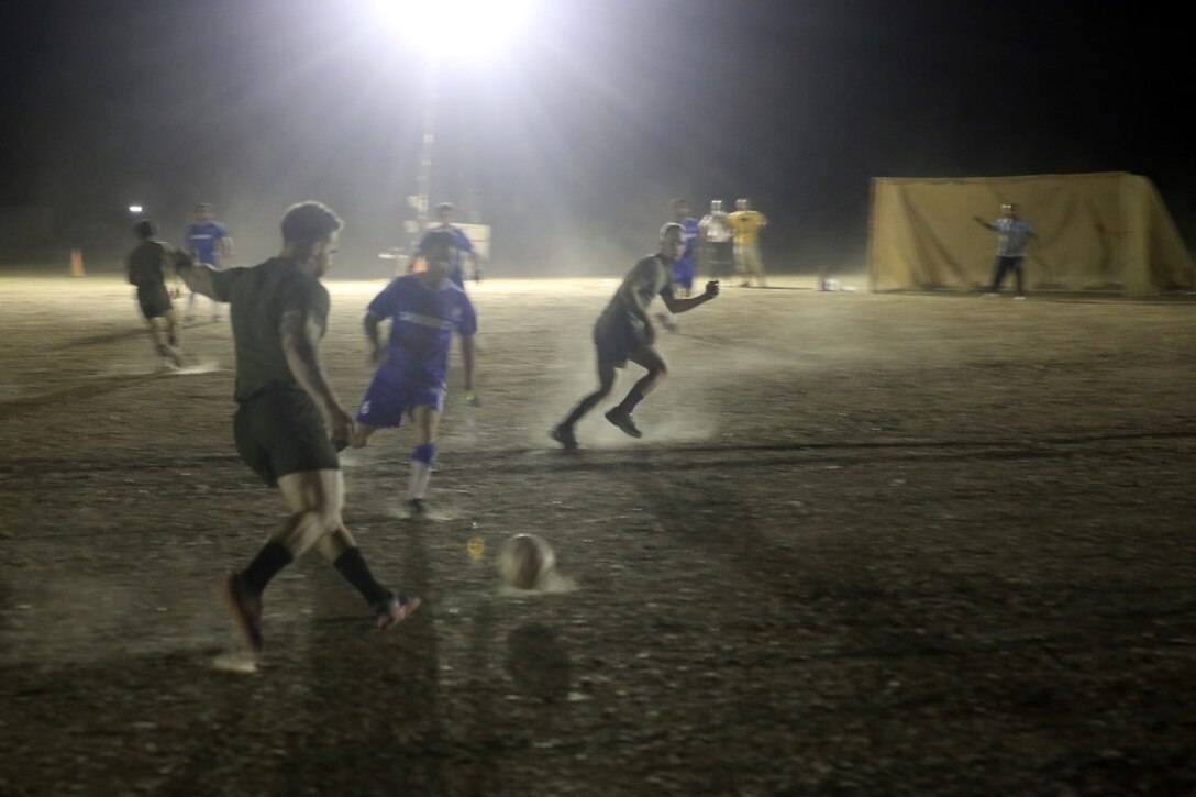 Corporal Ben McCabe, fire team leader, "Suicide" Charley Company, 1st Battalion, 7th Marine Regiment, and a native of North Canton, Ohio, prepares to pass the ball to a teammate during the championship game in the Dwyer World Cup aboard Camp Dwyer, Helmand province, Afghanistan, June 22, 2014. A total of four teams participated in the tournament to include Team America, Afghanistan, Jordan and the World Team (consisting of contractors on the camp). The Marines ultimately defeated the World Team during the final game and were the champions of the tournament.  (U.S. Marine Corps photo by Cpl. Joseph Scanlan / released)
