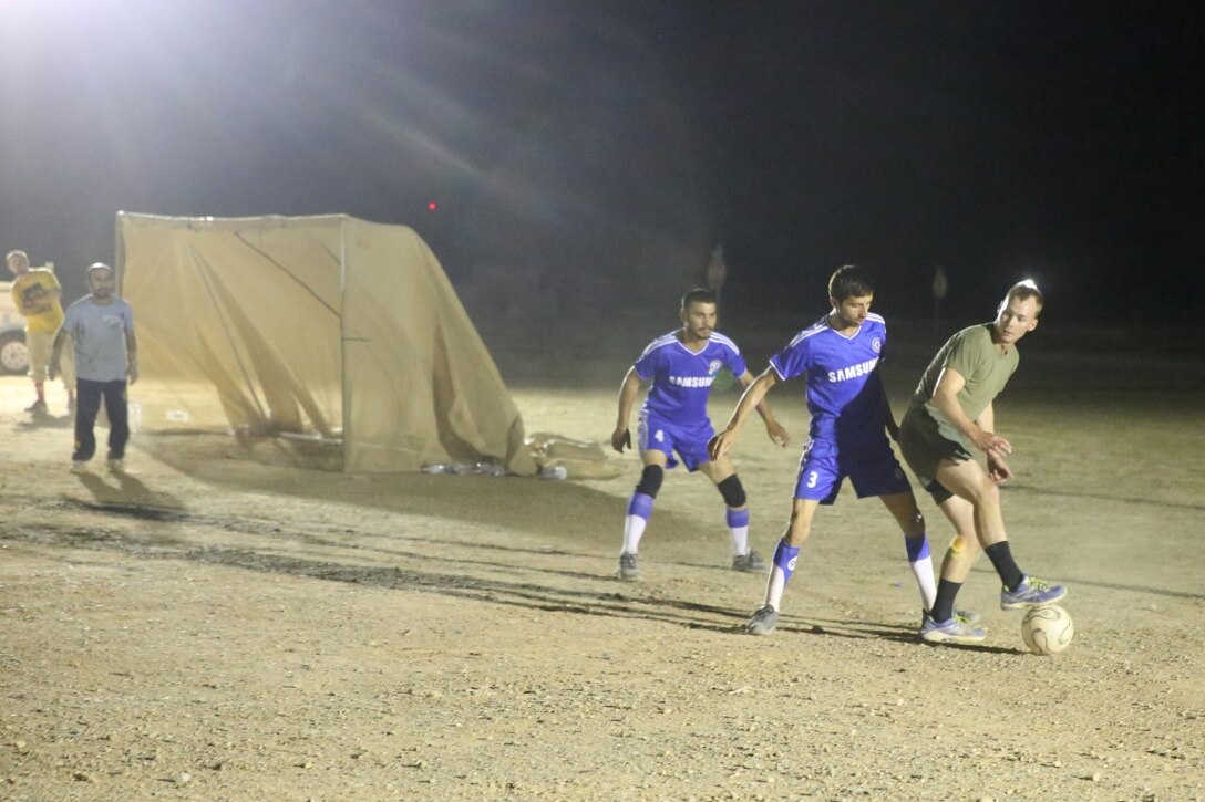 Corporal Kodie Artmayer, rifleman, "Suicide" Charley Company, 1st Battalion, 7th Marine Regiment, and a native of Harrison, Ohio, attempts to maneuver around a defender during the championship game in the Dwyer World Cup aboard Camp Dwyer, Helmand province, Afghanistan, June 22, 2014. A total of four teams participated in the tournament to include Team America, Afghanistan, Jordan and the World Team (consisting of contractors on the camp). The Marines ultimately defeated the World Team during the final game and were the champions of the tournament. (U.S. Marine Corps photo by Cpl. Joseph Scanlan / released)