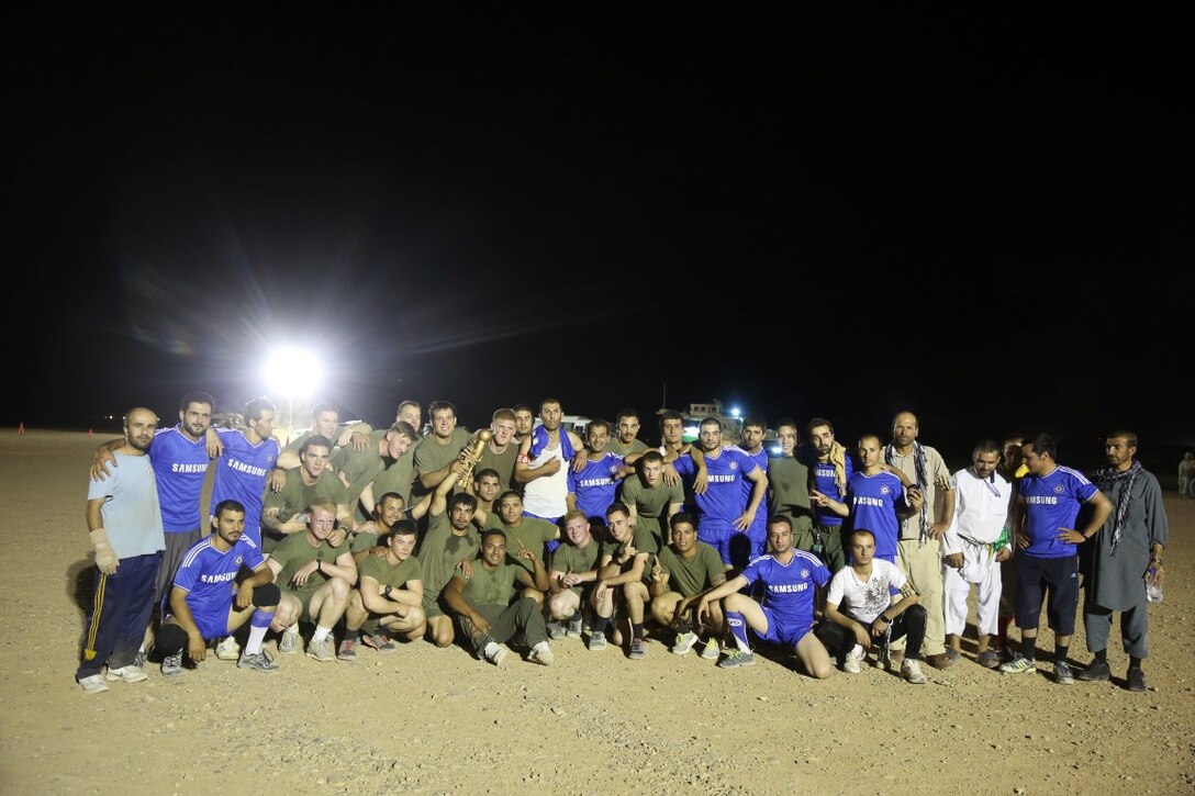 Marines with "Suicide" Charley Company, 1st Battalion, 7th Marine Regiment, pose for a photo with their opponents after winning the championship game in the Dwyer World Cup aboard Camp Dwyer, Helmand province, Afghanistan, June 22, 2014. A total of four teams participated in the tournament to include Team America, Afghanistan, Jordan and the World Team (consisting of contractors on the camp). The Marines ultimately defeated the World Team during the final game and were the champions of the tournament. (U.S. Marine Corps photo by Cpl. Joseph Scanlan / released)