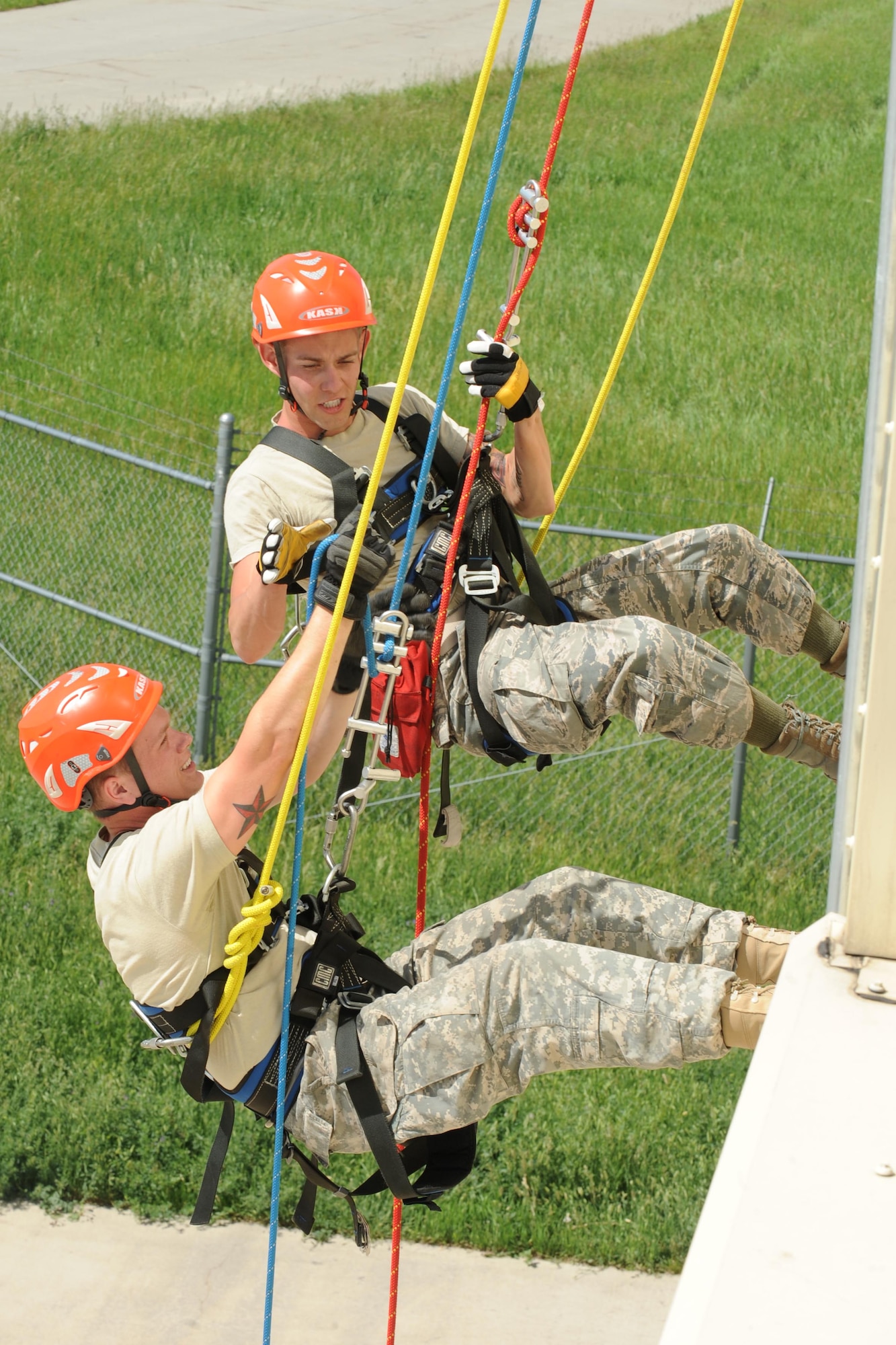 Spc. Ryan Krogstad, left, rappels from a building with the help of Senior Airman Kyle Brown during a Golden Coyote training exercise June 17, 2014, on Ellsworth Air Force Base, S.D. Airmen and South Dakota Army National Guard Soldiers participated in high rescue training to learn rappel and reconnaissance techniques to rescue victims that have been trapped in various locations. Krogstad is a SDNG 451st Engineer Detachment pumper operator and Brown is a 28th Civil Engineer Squadron driver operator. (U.S. Air Force photo/Airman 1st Class Rebecca Imwalle) 