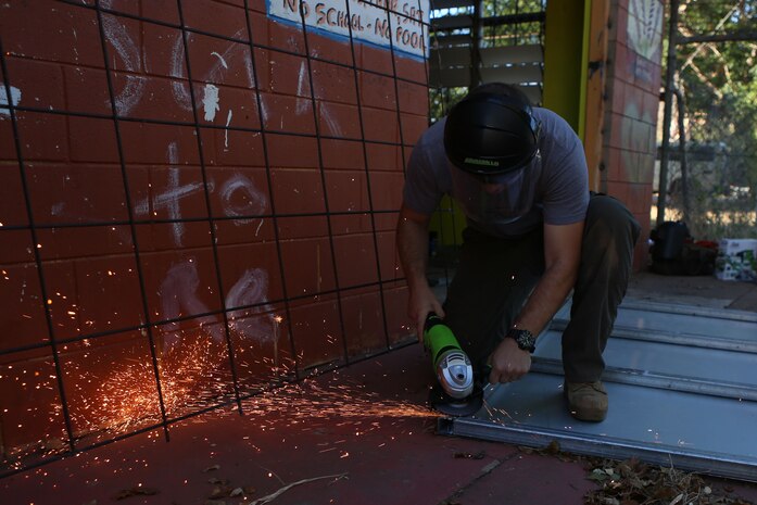 Petty Officer 3rd Class Dakotah Williams, a religious program specialist with Marine Wing Support Squadron 171, grinds down a door for a recreational center in the Beswick Community in the Northern Territory of Australia, June 21, 2014. Marines and sailors volunteered their time to assist in the building of the recreational center and help clean a local primary school.