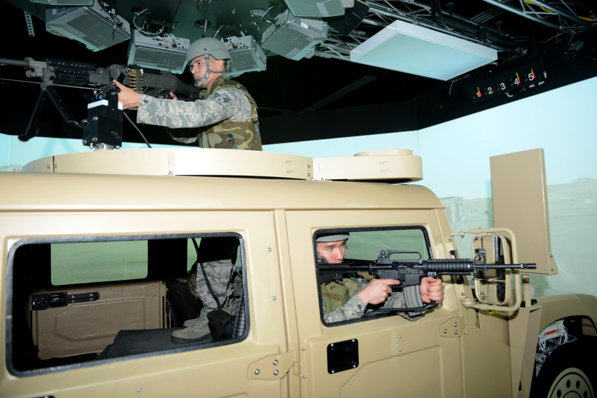 Senior Airman Jonathan Buenrostro and Senior Airman Aaron Thomas, 673d Contracting Squadron contract specialists, participate in the Reconfigurable Vehicle Tactical Trainer program on Joint Base Elmendorf-Richardson, Alaska, June 18, 2014. RVTT staff control virtual forces during the exercises, by adding and removing elements from the simulator experience. (U.S. Air Force photo/Airman 1st Class Ty-Rico Lea)