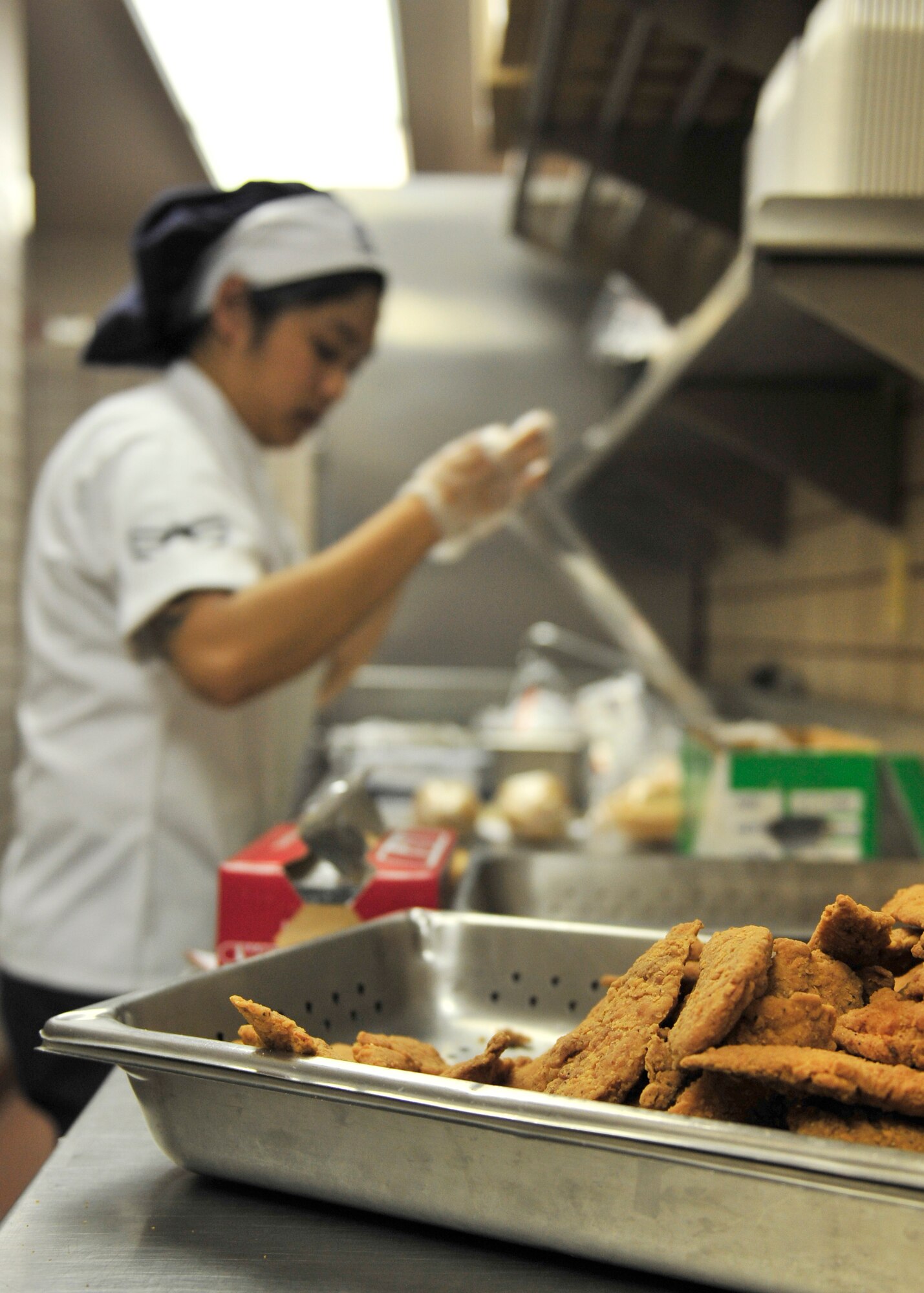 U.S. Air Force Airman 1st Class Alexis Merin, 354th Force Support Squadron shift worker, prepares flight meals with a tray of chicken at the Two Seasons Dining Facility during RED FLAG-Alaska 14-2, June 23, 2014, Eielson Air Force Base, Alaska. During RF-A, Merin prepares a minimum of 350 flight meals for lunch daily. (U.S. Air Force photo by Senior Airman Ashley Nicole Taylor/Released)