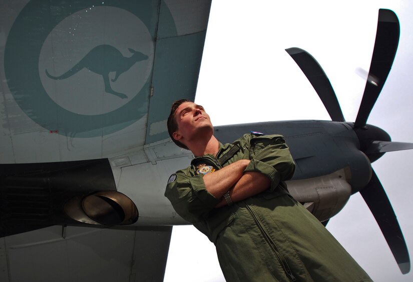 Royal Australian Air Force Flight Officer Angus Robertson, assigned to No. 37 Squadron based at RAAF Base Richmond, near Sydney, poses under the wing of his C-130 J Hercules aircraft on the tarmac at Joint Baser Elmendorf-Richardson, Alaska, Wednesday, June 25, 2014.  Robertson and his crew are at the base participating in Red Flag, a joint multi-national military exercise. (U.S. Air Force photo/Justin Connaher) 