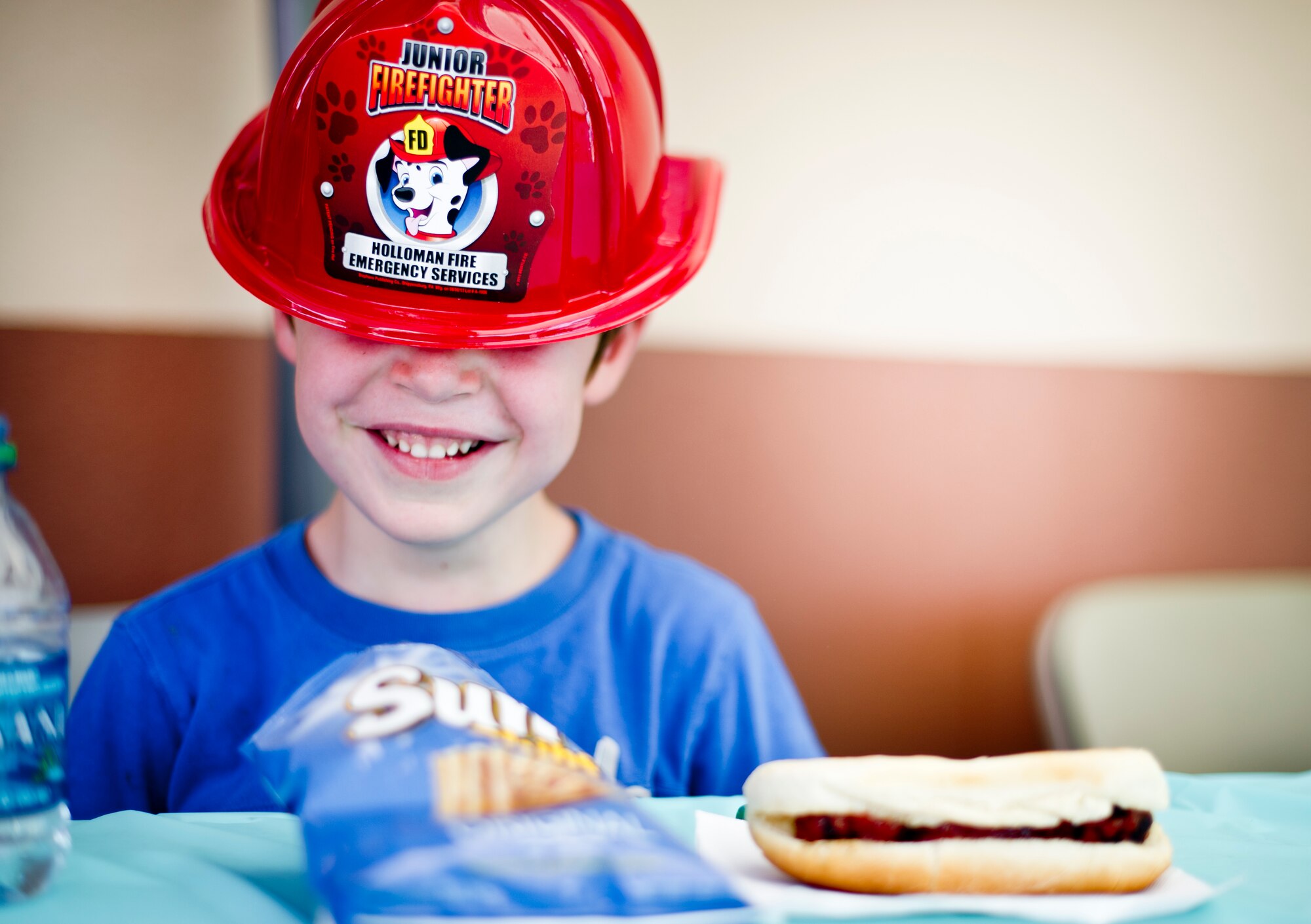 A child at Holloman Air Force Base N.M., wears a hat from the fire department while eating lunch during a commissary-hosted event to promote healthy living June 26, 2014.  The program is meant to emphasize healthy eating, and highlight different physical activities that are good for overall health and well-being. (U.S. Air Force photo by Staff Sgt Stacy Moless/Released)