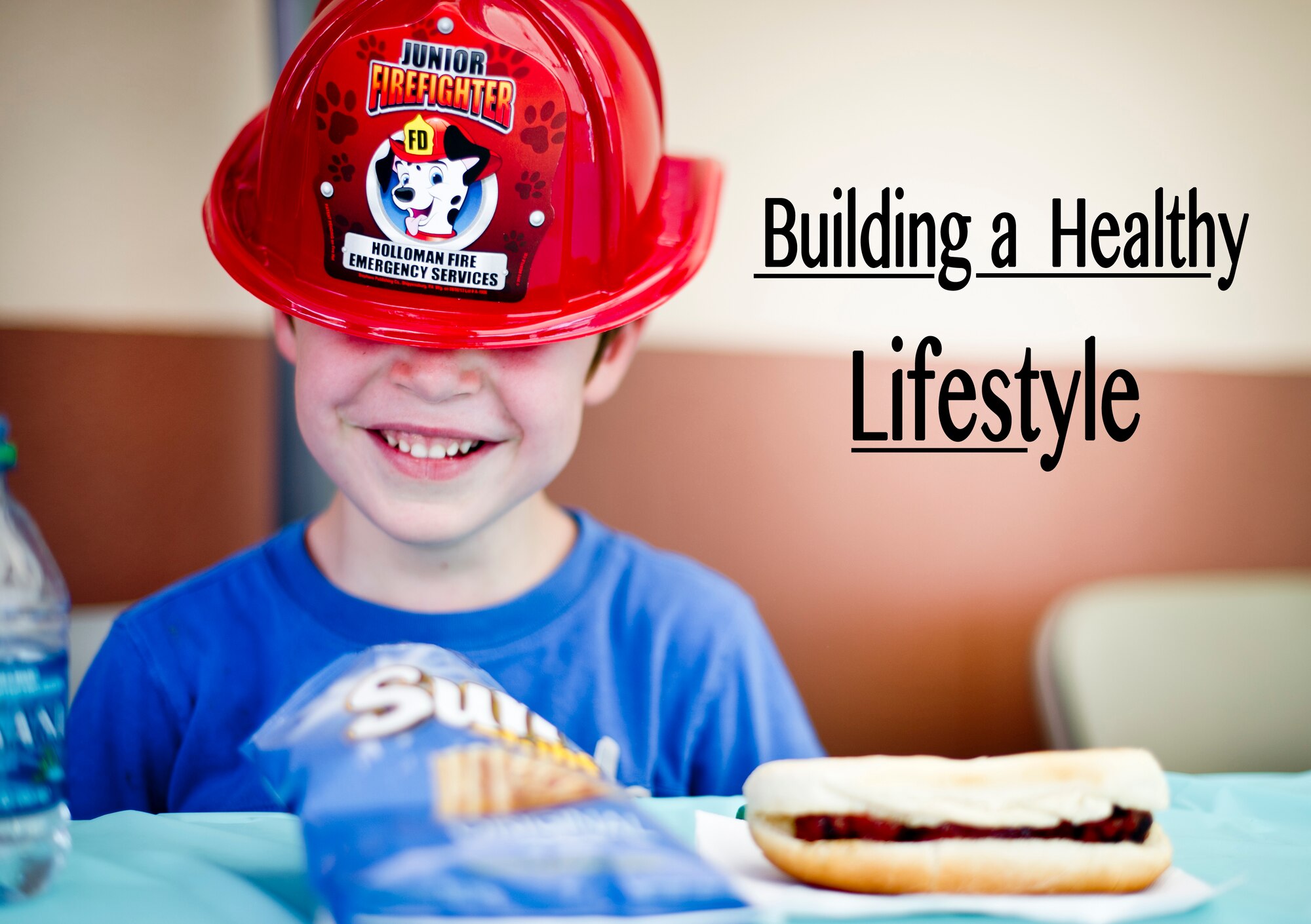 A child at Holloman Air Force Base N.M., wears a hat from the fire department while eating lunch during a commissary-hosted event to promote healthy living June 26, 2014.  The program is meant to emphasize healthy eating, and highlight different physical activities that are good for overall health and well-being. (U.S. Air Force photo by Staff Sgt Stacy Moless/Released)