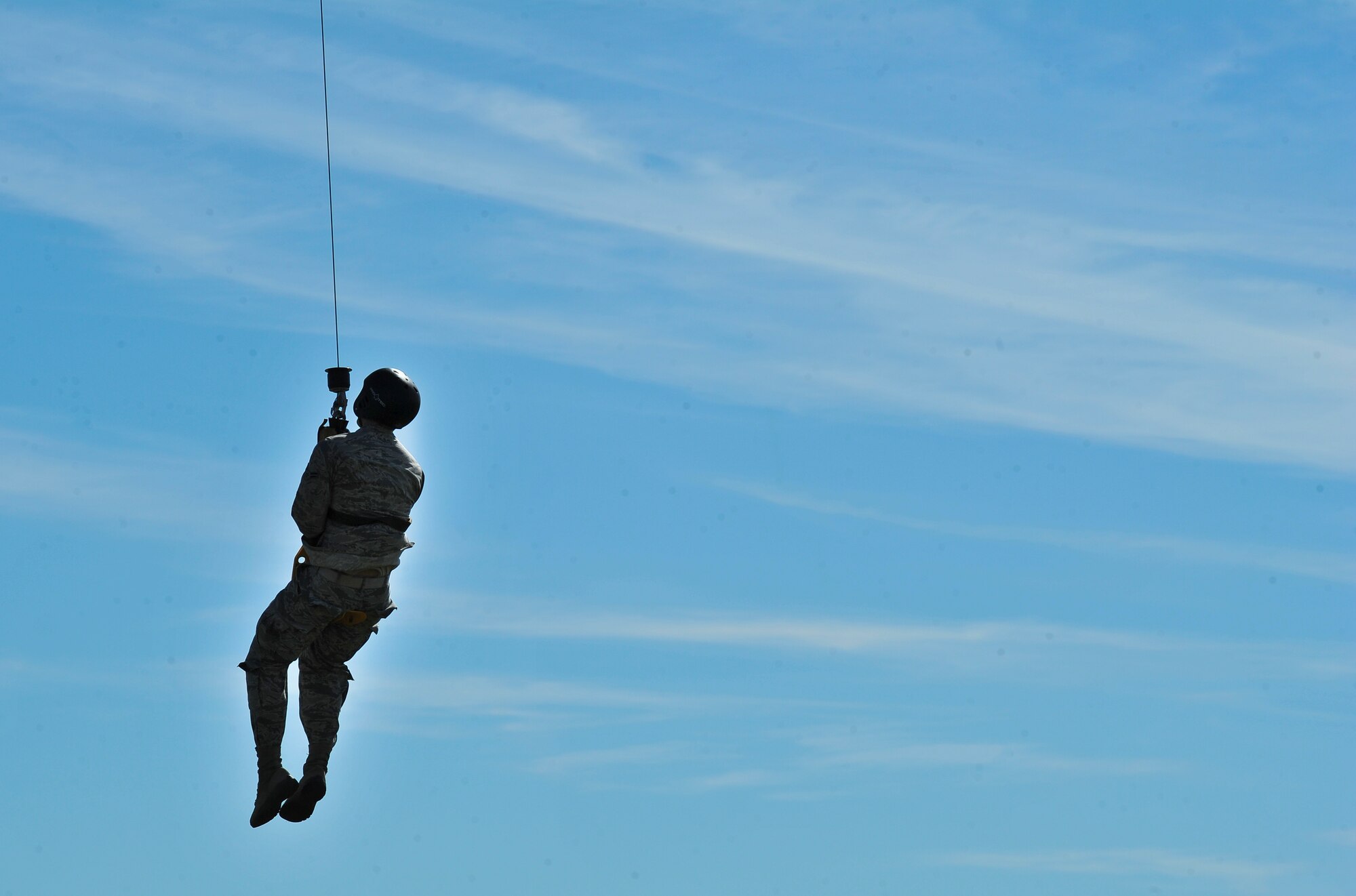 A Survival, Evasion, Resistance and Escape School student gets lifted by a forest penetrator hoist during training at Fairchild Air Force Base, Washington, June 25, 2014. The SV-80B course gives students an opportunity to experience firsthand how to safely be hoisted into a helicopter. Flight crews assigned to the 36th Rescue Flight assist students attending the 17-day school by providing airlift for training and in the event of an accident.  (U.S. Air Force photo by Staff Sgt. Alexandre Montes/Released)