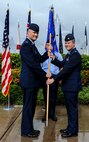Col. David Kirkendall, 647th Air Base Group commander, passes the guidon to Col. Jeffrey Guimarin, 747th Communications Squadron commander, during a change of command ceremony at the Missing Man Formation on Joint Base Pearl Harbor-Hickam, Hawaii, June 26, 2014. During the ceremony, Guimarin took the reins from Lt. Col. David Hillman. (U.S. Air Force photo/Tech. Sgt. Terri Paden)