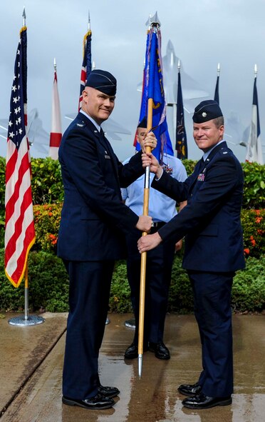 Col. David Kirkendall, 647th Air Base Group commander, passes the guidon to Col. Jeffrey Guimarin, 747th Communications Squadron commander, during a change of command ceremony at the Missing Man Formation on Joint Base Pearl Harbor-Hickam, Hawaii, June 26, 2014. During the ceremony, Guimarin took the reins from Lt. Col. David Hillman. (U.S. Air Force photo/Tech. Sgt. Terri Paden)