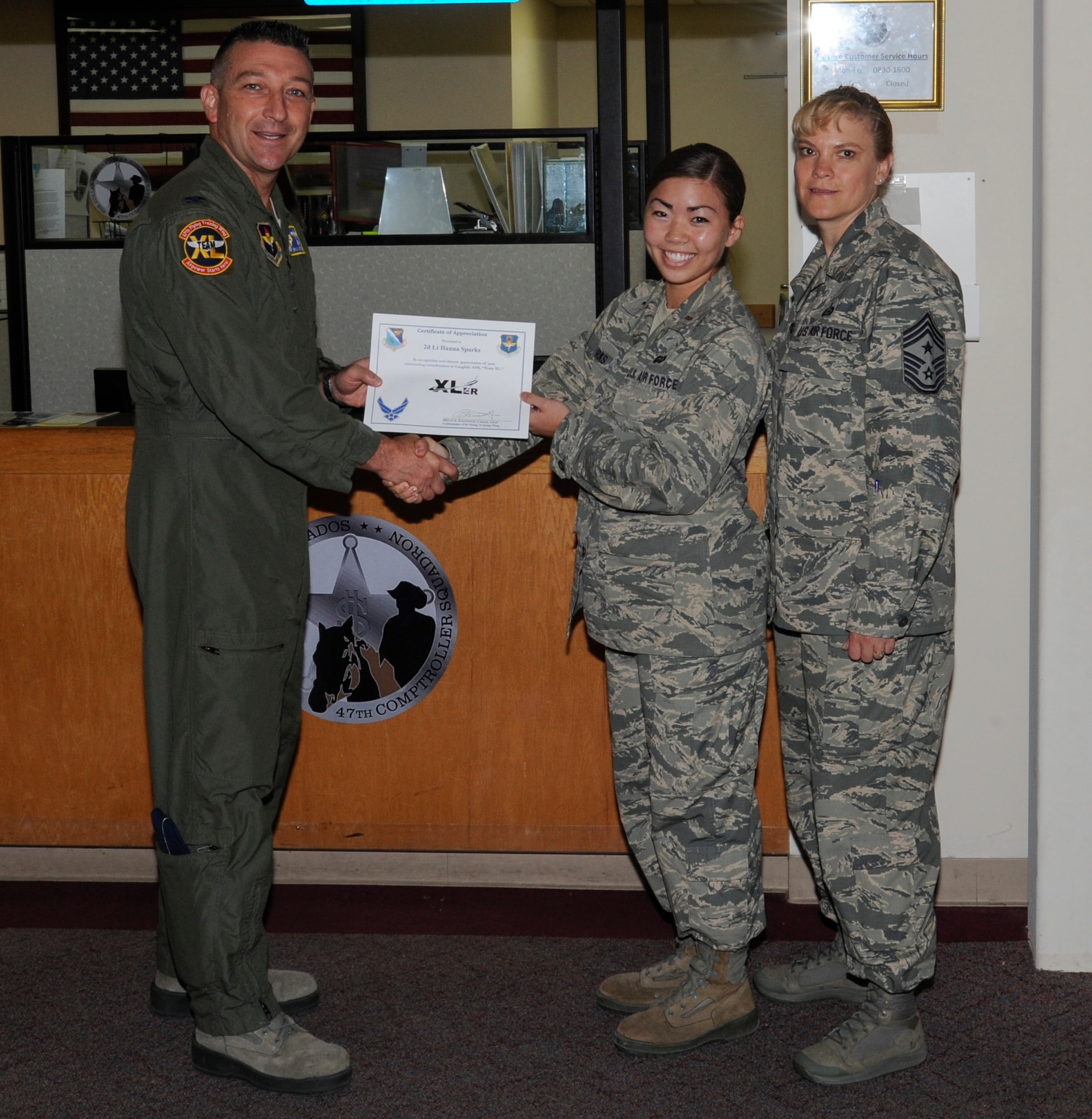 Second Lt. Hanna Sparks, center, 47th Force Support Squadron chief of military personnel section, poses with Col. Brian Hastings, left, 47th Flying Training Wing commander, and Chief Master Sgt. Teresa Clapper, right, 47th FTW command chief, after being presented the XLer of the week award here June 26, 2014. The XLer is a weekly award chosen by wing leadership and given to those who consistently make outstanding contributions to their unit and Laughlin. (U.S. Air Force photo/Airman 1st Class Jimmie D. Pike)(Released)