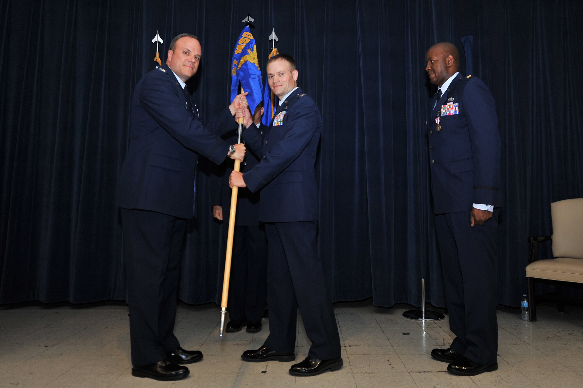 ALTUS AIR FORCE BASE, Okla. U.S. Air Force Col. Michael Greiner, 97th Mission Support Group commander, passes the 97th Contracting Flight guidon to U.S. Air Force Capt. Jon Hobart, 97th Contracting Flight commander, during a change of command and re-designation ceremony inside the Freedom Community Center June 25, 2014. The new contracting flight will provide the same support for the 97th Air Mobility Wing. (U.S. Air Force photo by Senior Airman Dillon Davis/Released)