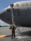 Col. Johnny Roscoe, 15th Wing commander, is doused with water by Capt. Nate Cavender, 15th Wing executive officer, on the Joint Base Pearl Harbor-Hickam flightline after completing his final training mission in the C-17 Globemaster III June 24, 2014. The mission was Roscoe’s “fini-flight,” a ceremonial final flight for Air Force pilots. Roscoe is retiring after 26 years of Air Force service. (U.S. Air Force photo/Tech. Sgt. Terri Paden)