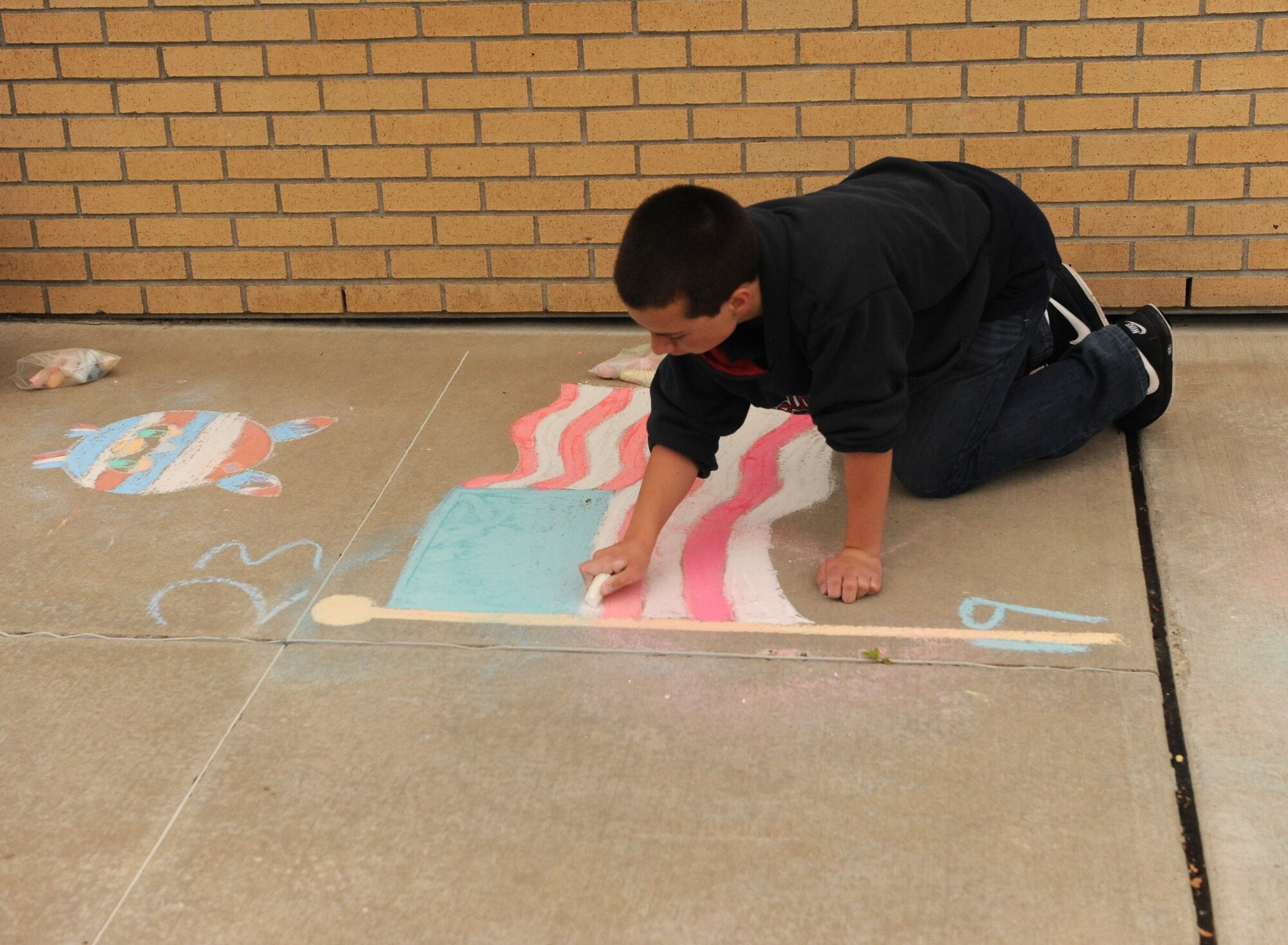 A child draws an American flag during the 15th annual Chalk It Up sidewalk chalk art competition June 26 at Malmstrom Air Force Base Youth Center. This year’s theme was ‘I am an American’. (U.S. Air Force photo/ Airman 1st Class Joshua Smoot)