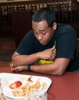 U.S. Air Force Senior Airman Christopher Lee stares at his plate after finishing the 2.5-pound monster burger during a Man vs. Food competition at Moody Air Force Base, Ga., June 25, 2014. Although Lee didn’t finish all the fries, he was still named the winner for eating the whole burger. (U.S. Air Force photo by Senior Airman Jarrod Grammel/Released)
