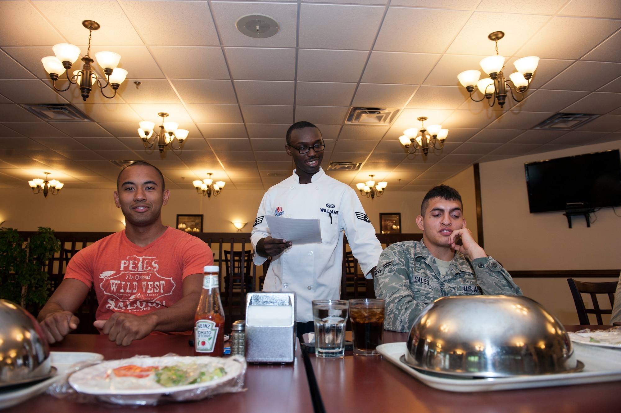 U.S. Air Force Senior Airman Arthur Williams, middle, 23d Force Support Squadron food services specialist, introduces Airman 1st Class Alberto Sales, right, and Airman 1st Class Calvin Rivera before the start of a Man vs. Food competition at Moody Air Force Base, Ga., June 25, 2014. The four competitors had one hour to eat a 2.5-pound cheeseburger and a plate of fries. (U.S. Air Force photo by Senior Airman Jarrod Grammel/Released) 
