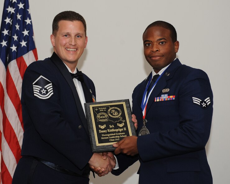 Senior Airman Danny Riddlespriger, 2nd Bomb Wing Judge Advocates Office, receives the Distinguished Graduate Award from Master Sgt. Joshua Sandifer, 2nd Maintenance Squadron, during the Airman Leadership School Class 14-5 Graduation on Barksdale Air Force Base, La., June 19, 2014. (U.S. Air Force photo/Senior Airman Benjamin Gonsier)