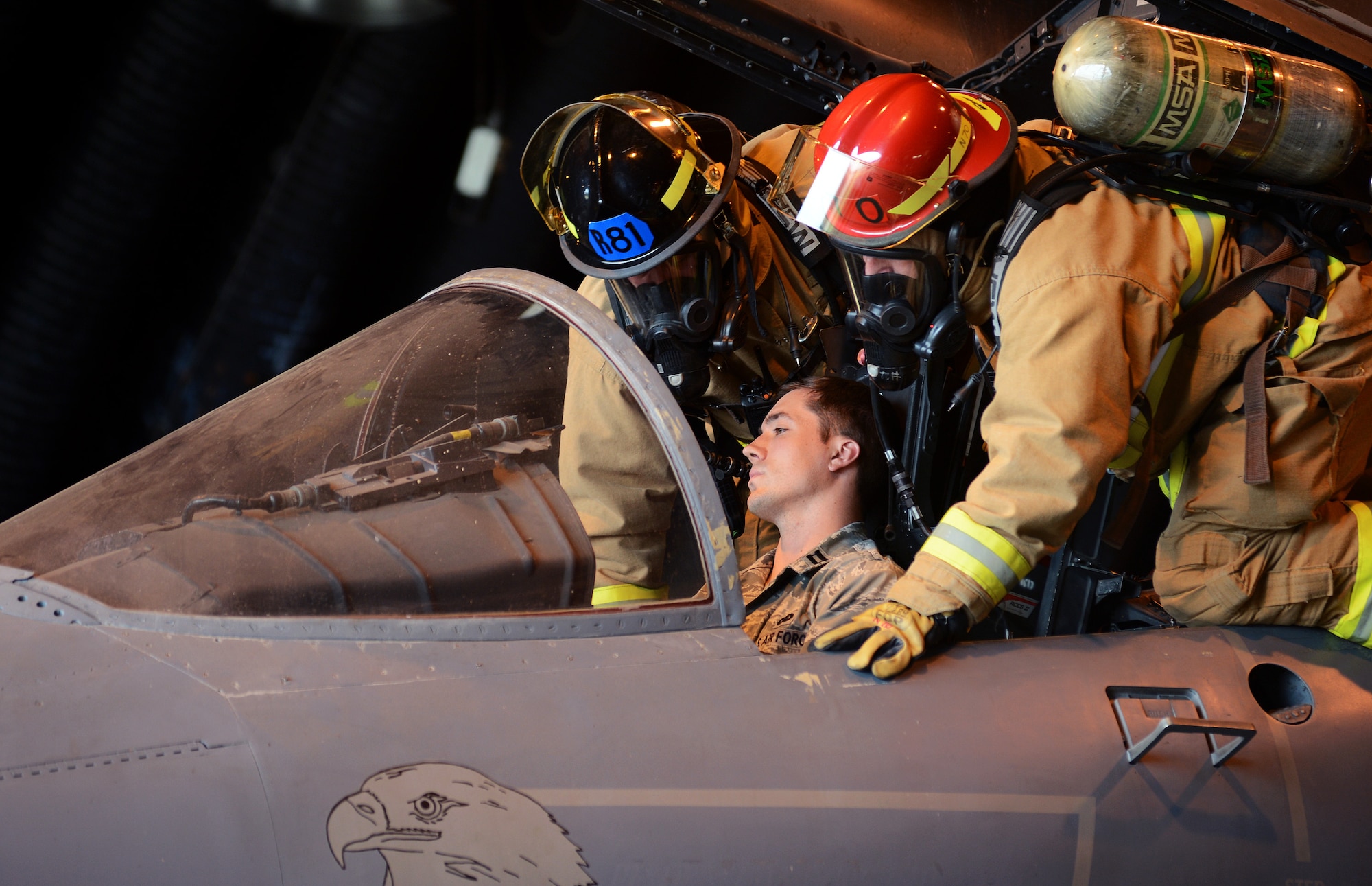 Two 48th Civil Engineer Squadron firefighters remove Capt. Benjamin Farber, 48th Contracting Squadron, from the cockpit of an F-15E Strike Eagle in a protected aircraft shelter during a mission assurance exercise at Royal Air Force Lakenheath, England, June 24, 2014. As one of many scenarios during the three-day training event, the firefighters responded to a fire to rescue a simulated wounded pilot. (U.S. Air Force photo by Staff Sgt. Thomas Trower/Released)