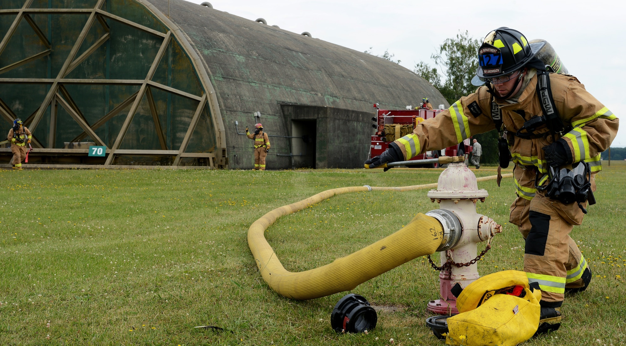 Airman 1st Class Matthew McPherson, 48th Civil Engineer Squadron firefighter, opens water flow during a simulated aircraft fire in a protected aircraft shelter at Royal Air Force Lakenheath, England, June 24, 2014. As one of many scenarios during the three-day 48th Fighter Wing Mission Assurance exercise, the firefighters contained the fire and evacuated the pilot to safety. (U.S. Air Force photo by Staff Sgt. Thomas Trower/Released)